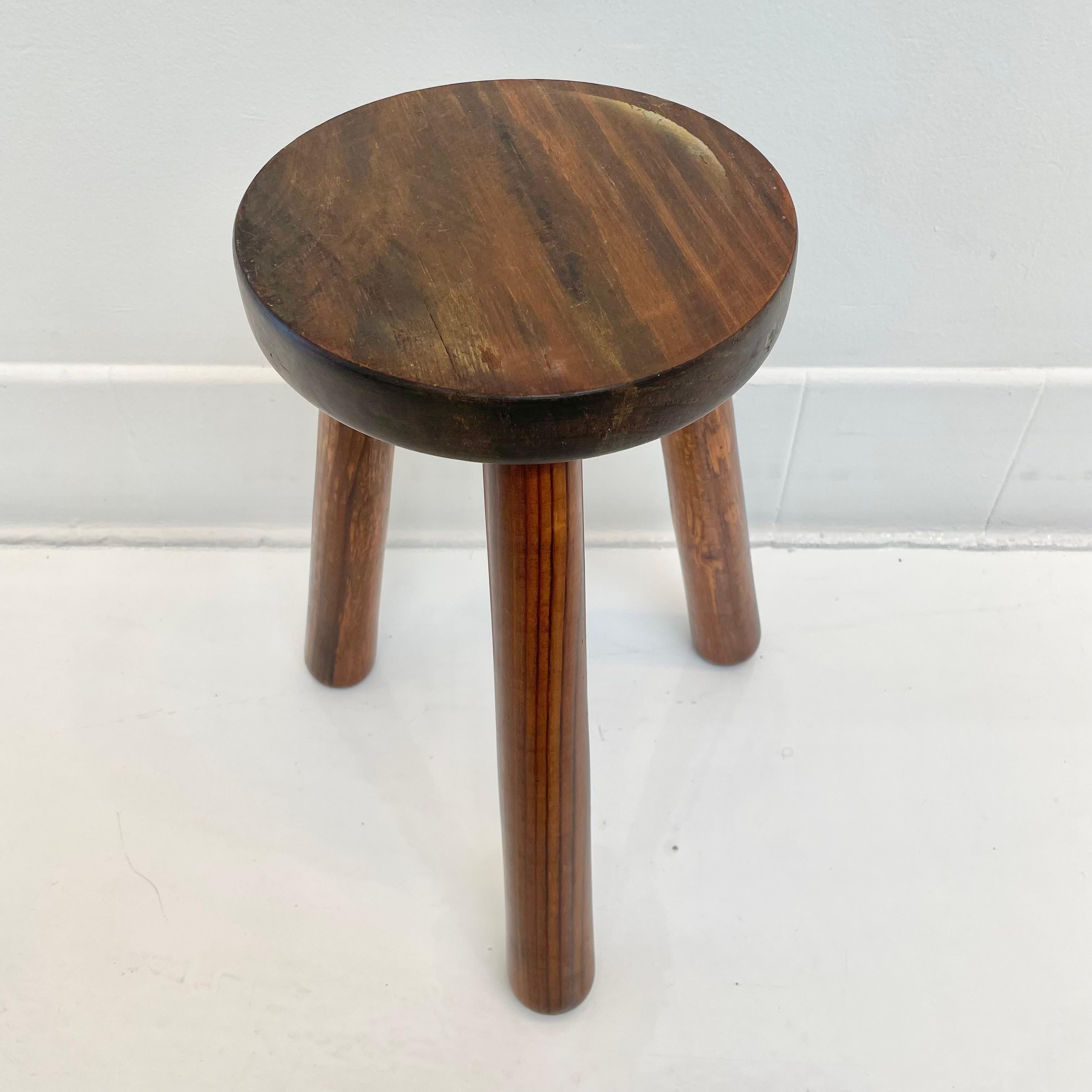 Beautiful 3 legged stool made in France, circa 1960s. Round seat held up by three sturdy wooden legs that are screwed into metal anchors in the seat giving this stool added strength and stability. Dark patina and age have made this stool a perfect