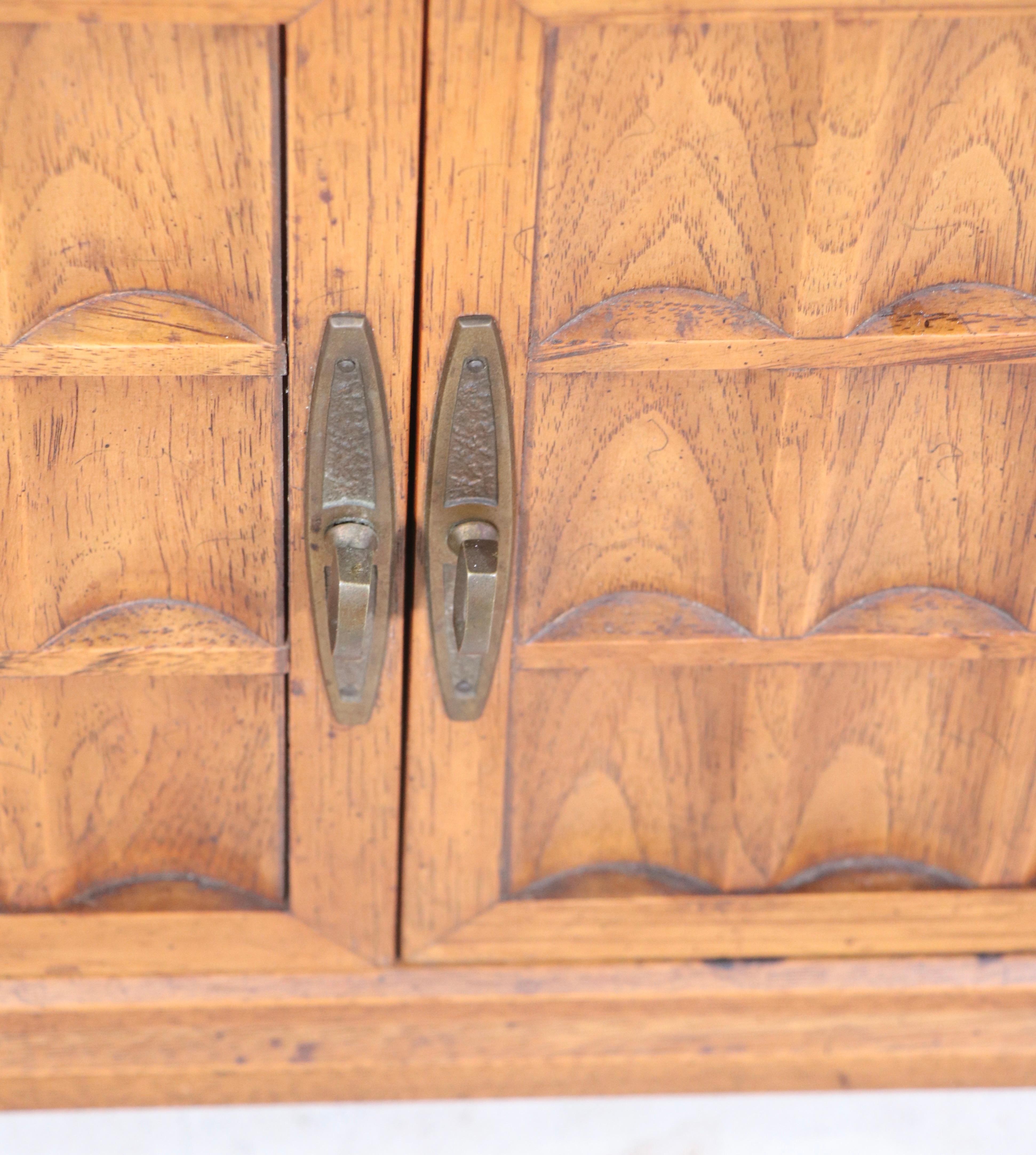 Armoire à deux portes de belle facture, avec une façade en bois sculpté et des poignées décoratives en métal. Le meuble est en très bon état d'origine, ne présentant qu'une légère usure cosmétique, normale et cohérente avec l'âge, marqué Heritage,