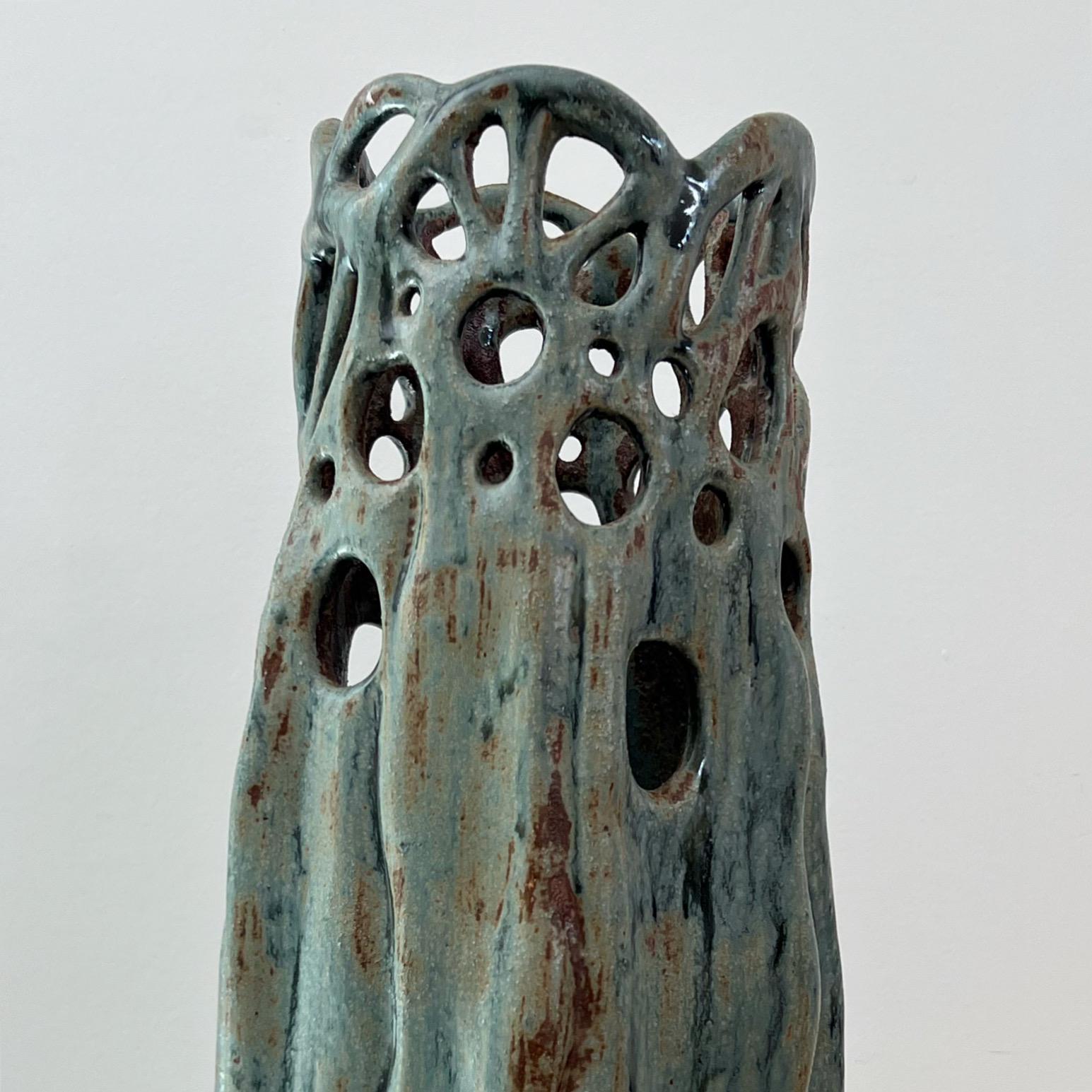 Eine hohe brutalistische Keramikvase, 1990er Jahre. Stil von Sally Bowen Prange. Trypophobiker aufgepasst: Die obere Hälfte der Vase ist mit Löchern übersät. Gedämpftes Teal und Denim mit karamellfarbenen Akzenten. Signiert von Wally Wiseman, '97.