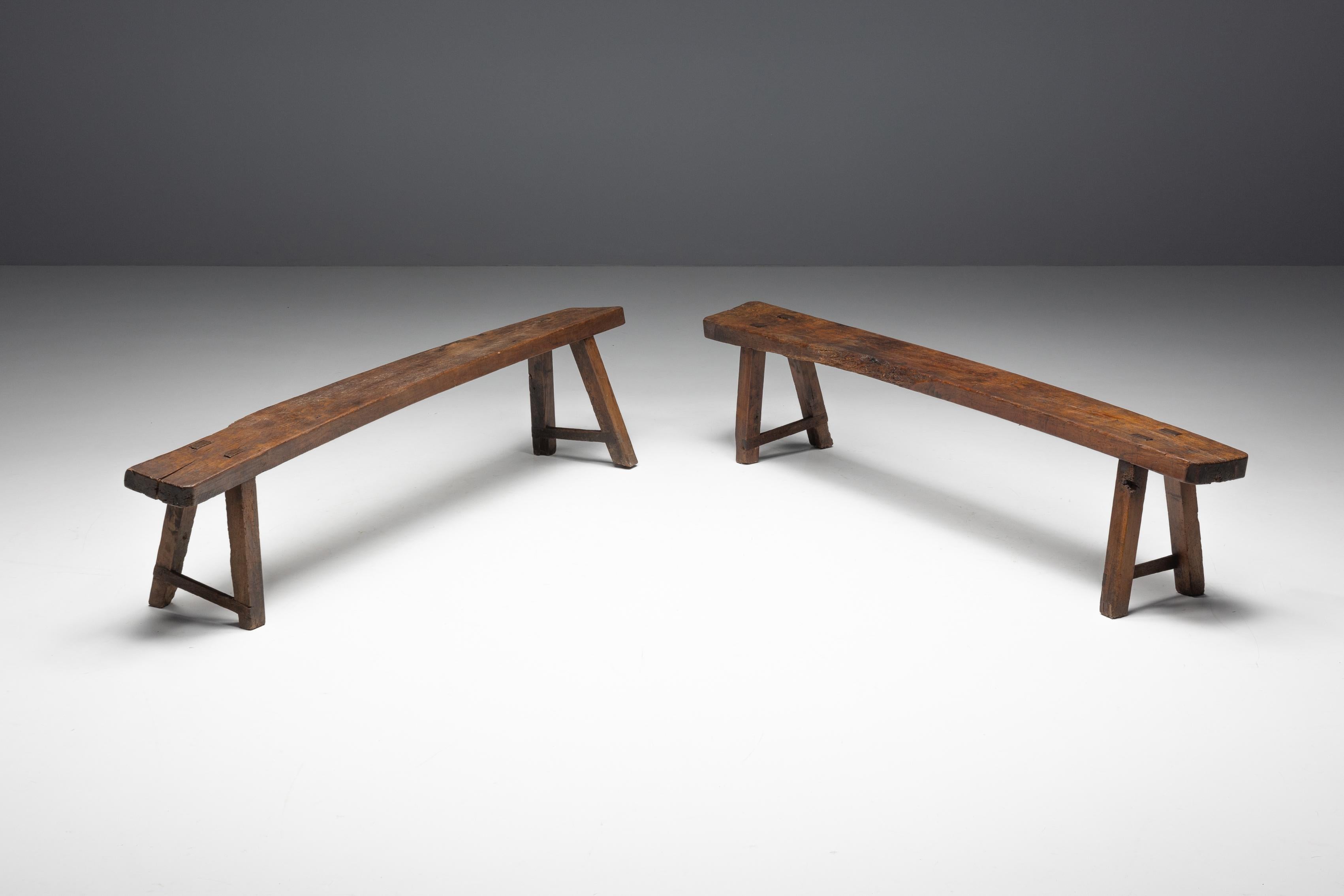 Panche brutaliste francesi del XIX secolo, che riflettono l'essenza della bellezza wabi-sabi nella loro forma imperfetta. Queste panchine presentano una robusta struttura in legno scuro e una patina ricca e consumata dal tempo che racconta la storia