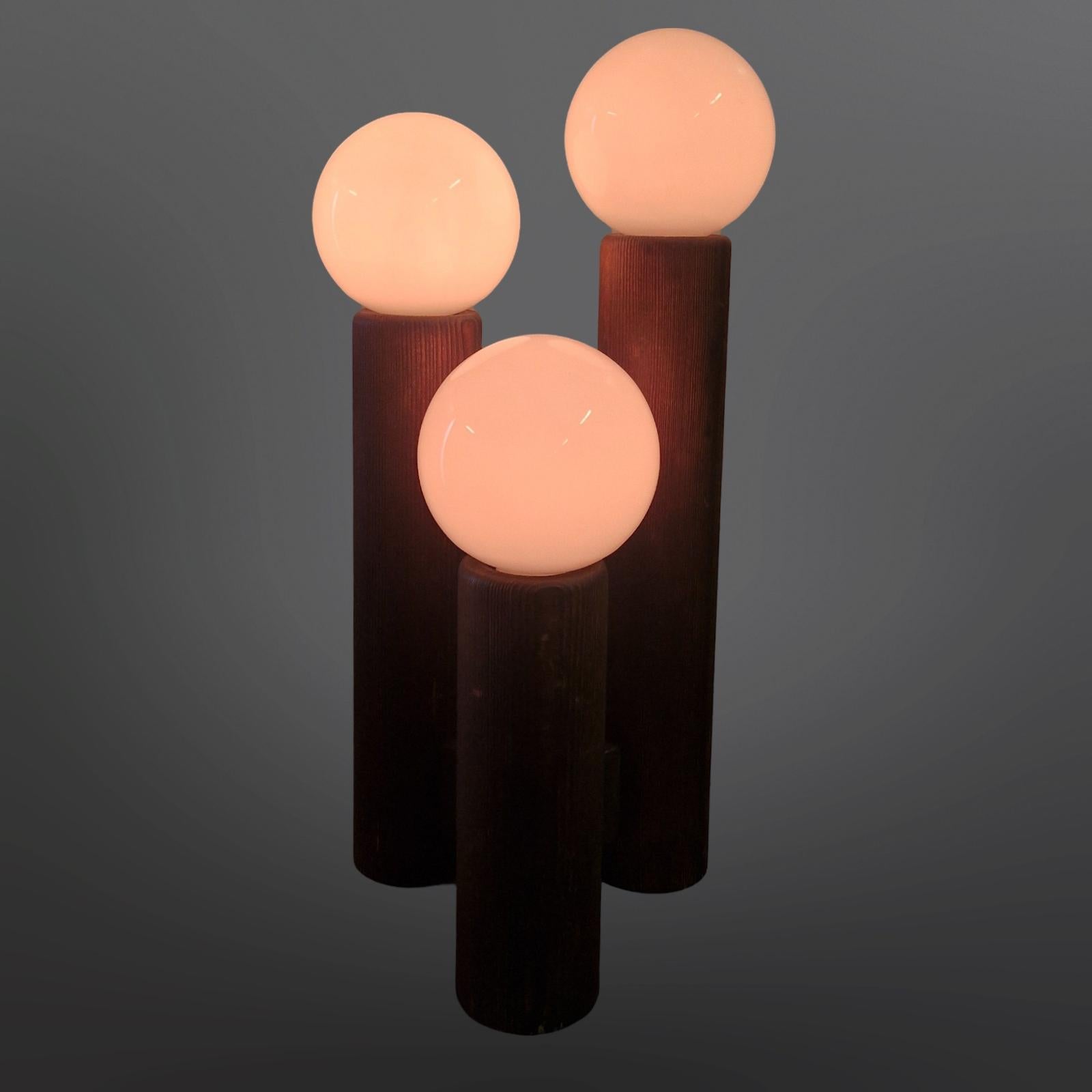 Lampada da tavolo a tre colonne. Prodotto dall'azienda svizzera Temde negli anni '70. Realizzato in robusto pino massiccio. Le tre colonne misurano 40, 53 e 59 cm di altezza. I globi misurano 14 cm di diametro. La larghezza e la profondità totali
