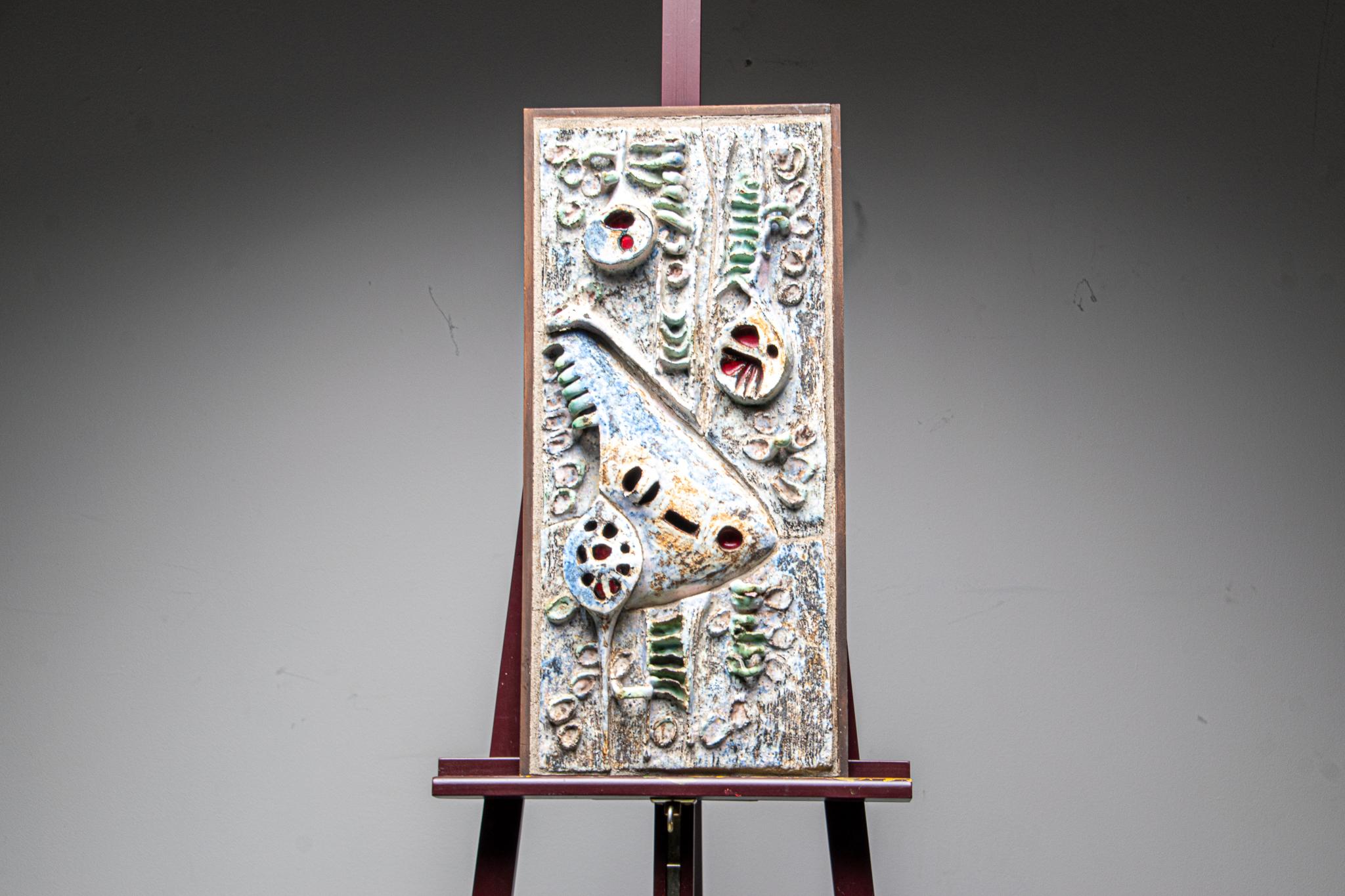 Brutalist ceramic wall mounted sculpture.

The piece is mounted in a simple wooden frame. Hand made ceeramic sculptings finshied with hand painted decoration.

In perfect condition.