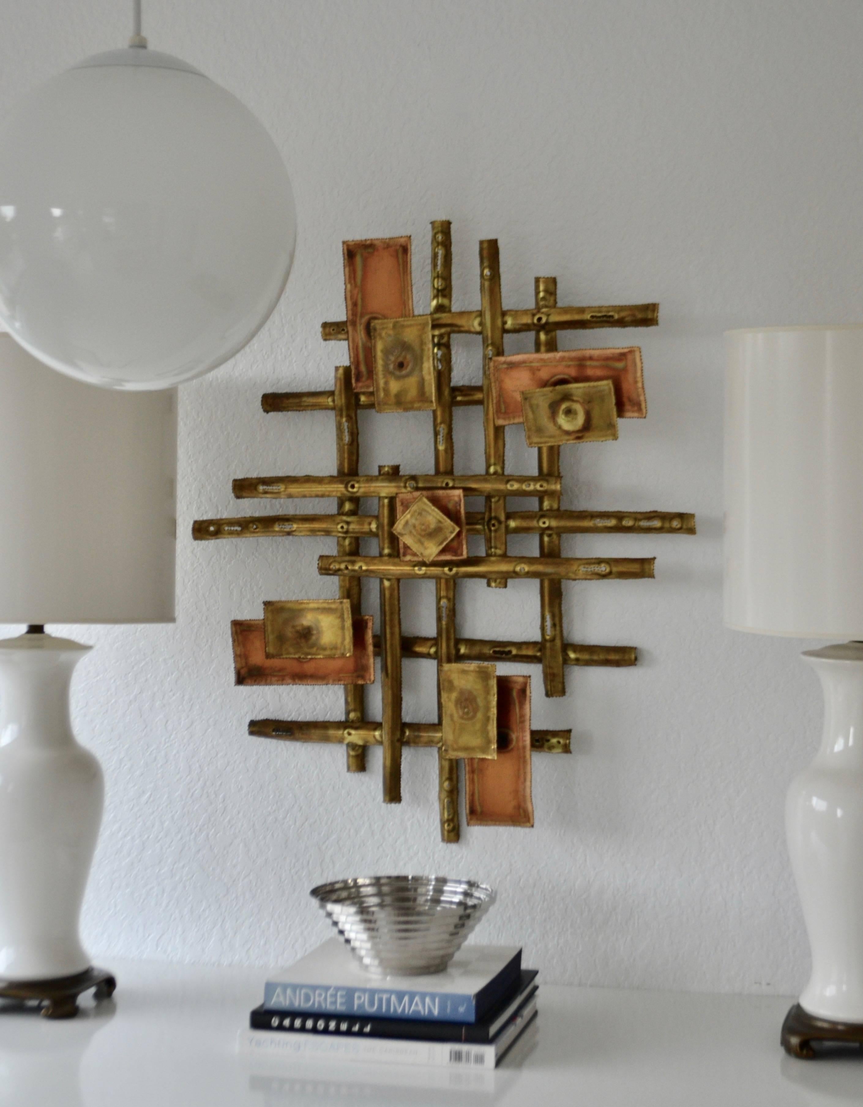 Stunning midcentury torch-cut mixed metal wall sculpture, circa 1960s. This striking Brutalist sculpture of polished and patinated brass is designed of layered rods and floating panels. Can be hung vertically or