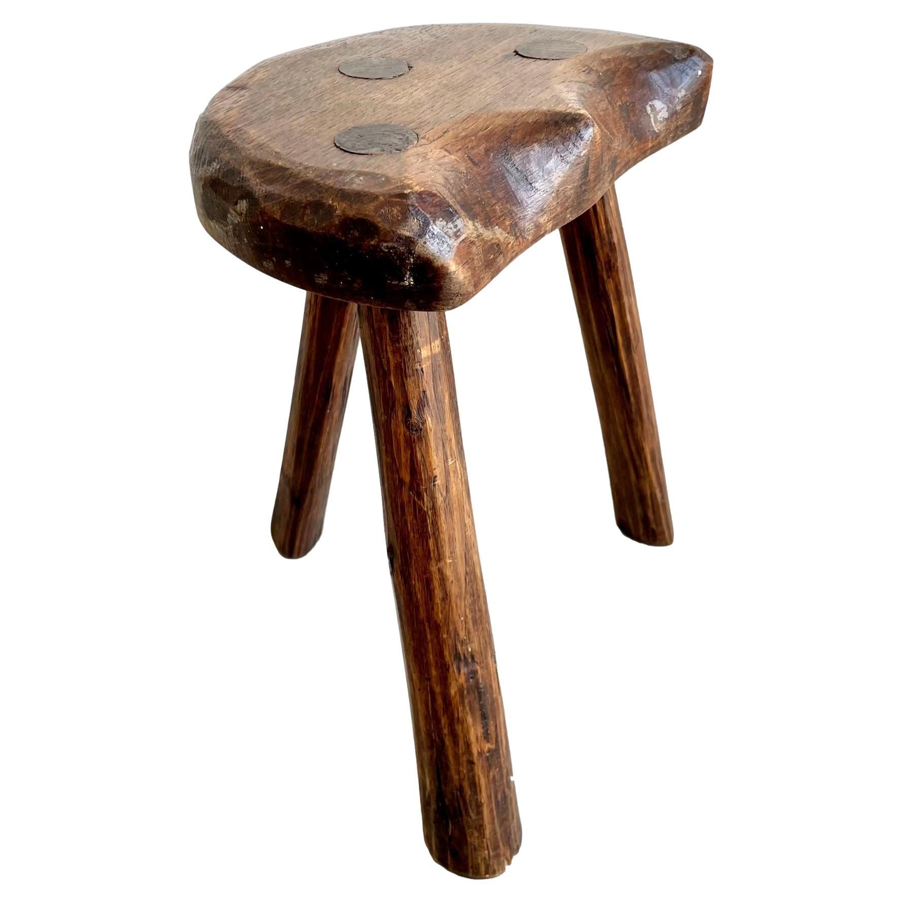 Brutalist wooden tripod stool made in France, circa 1950s. Substantial and chunky seat with sturdy legs. This stool has an impressive crescent moon shaped seat with great character and lines. Darkened patina and grain to the wood. Perfect for books