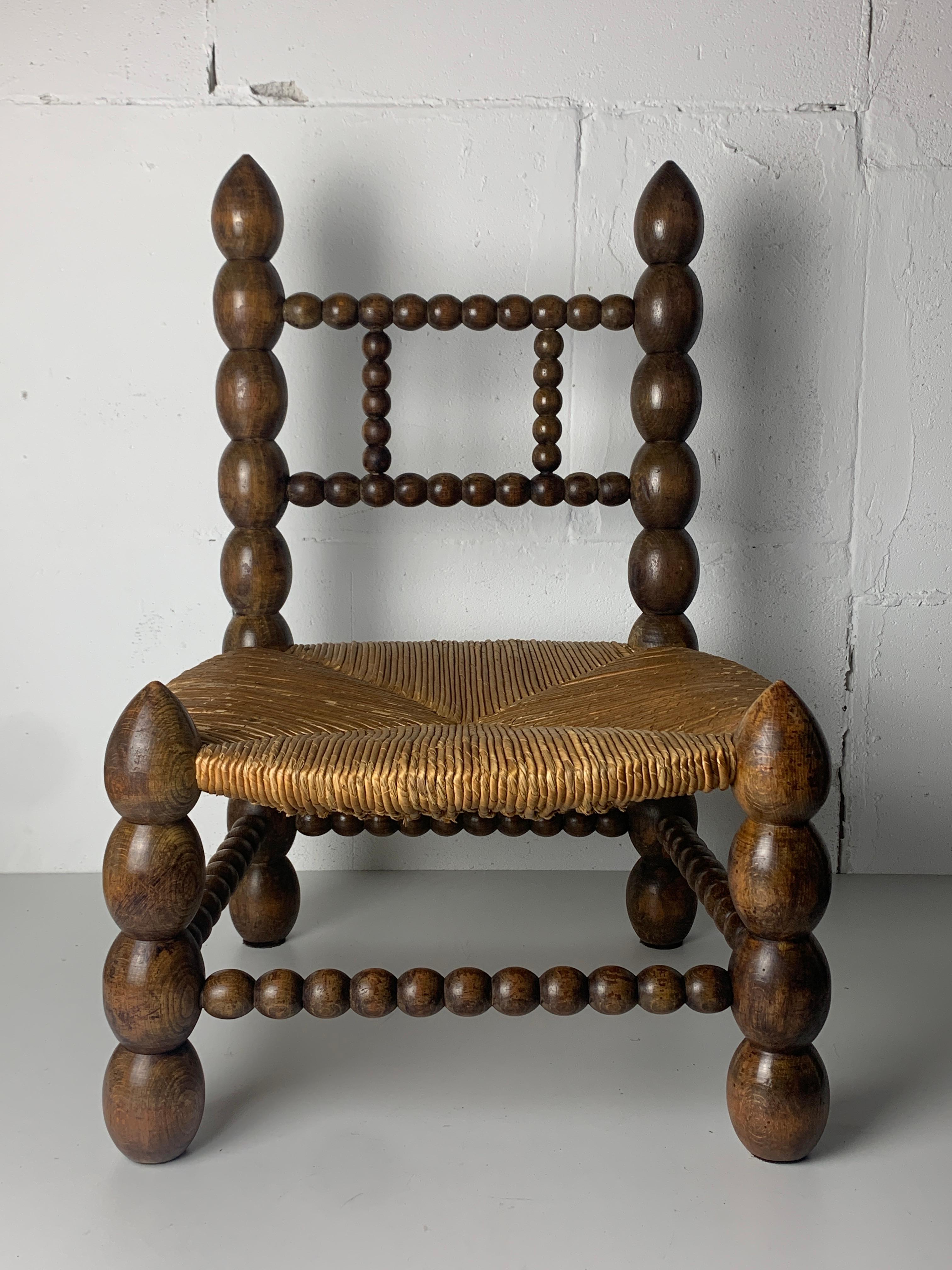 Rustic Brutalist wood turned bobbin low rush chair in the style of Charles Dudouyt
