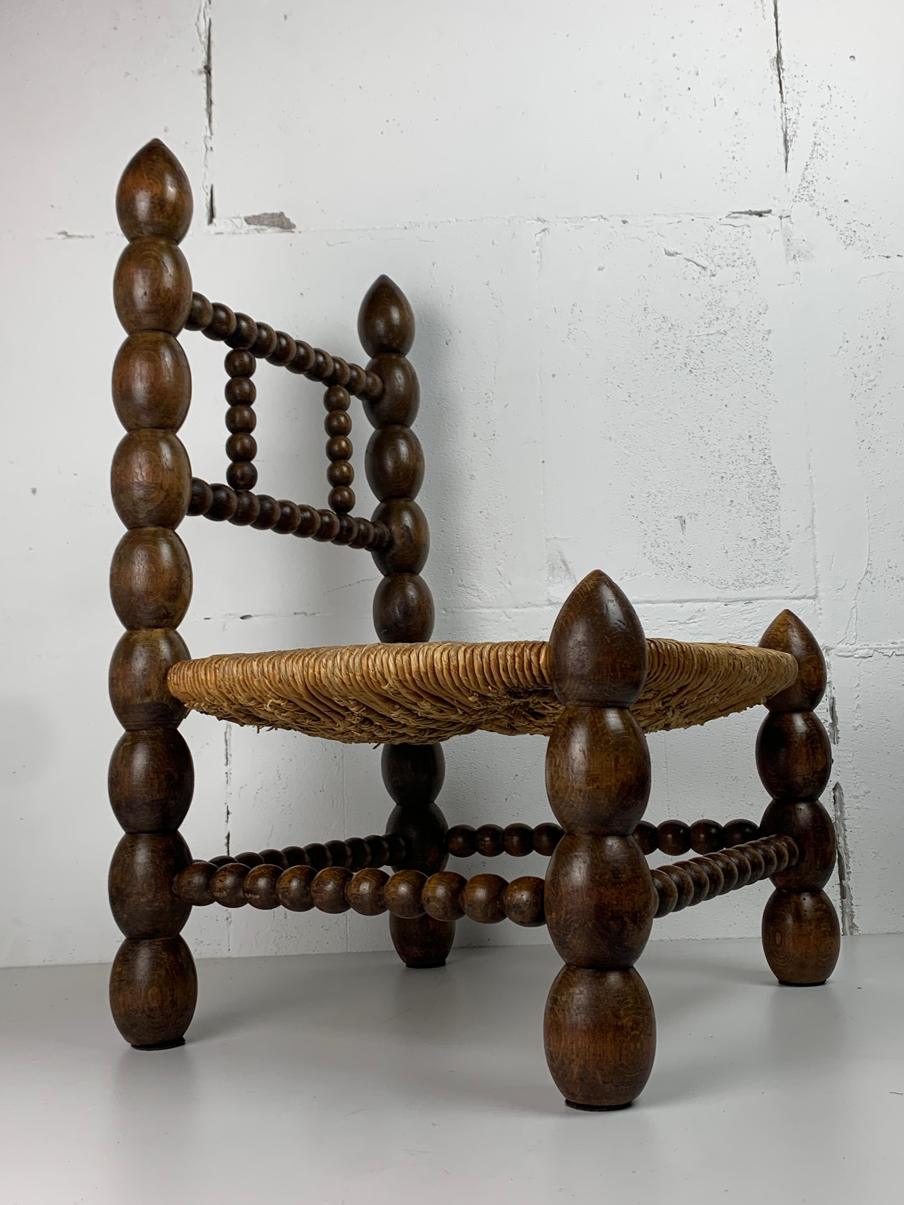 Turned Brutalist wood turned bobbin low rush chair in the style of Charles Dudouyt