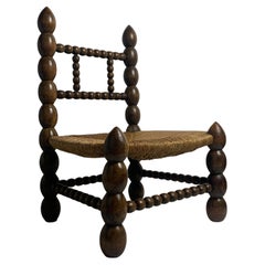 Brutalist wood turned bobbin low rush chair in the style of Charles Dudouyt