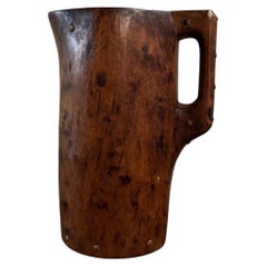 Brutalist wooden pitcher with monochrome finish, enhanced with nails, folk art