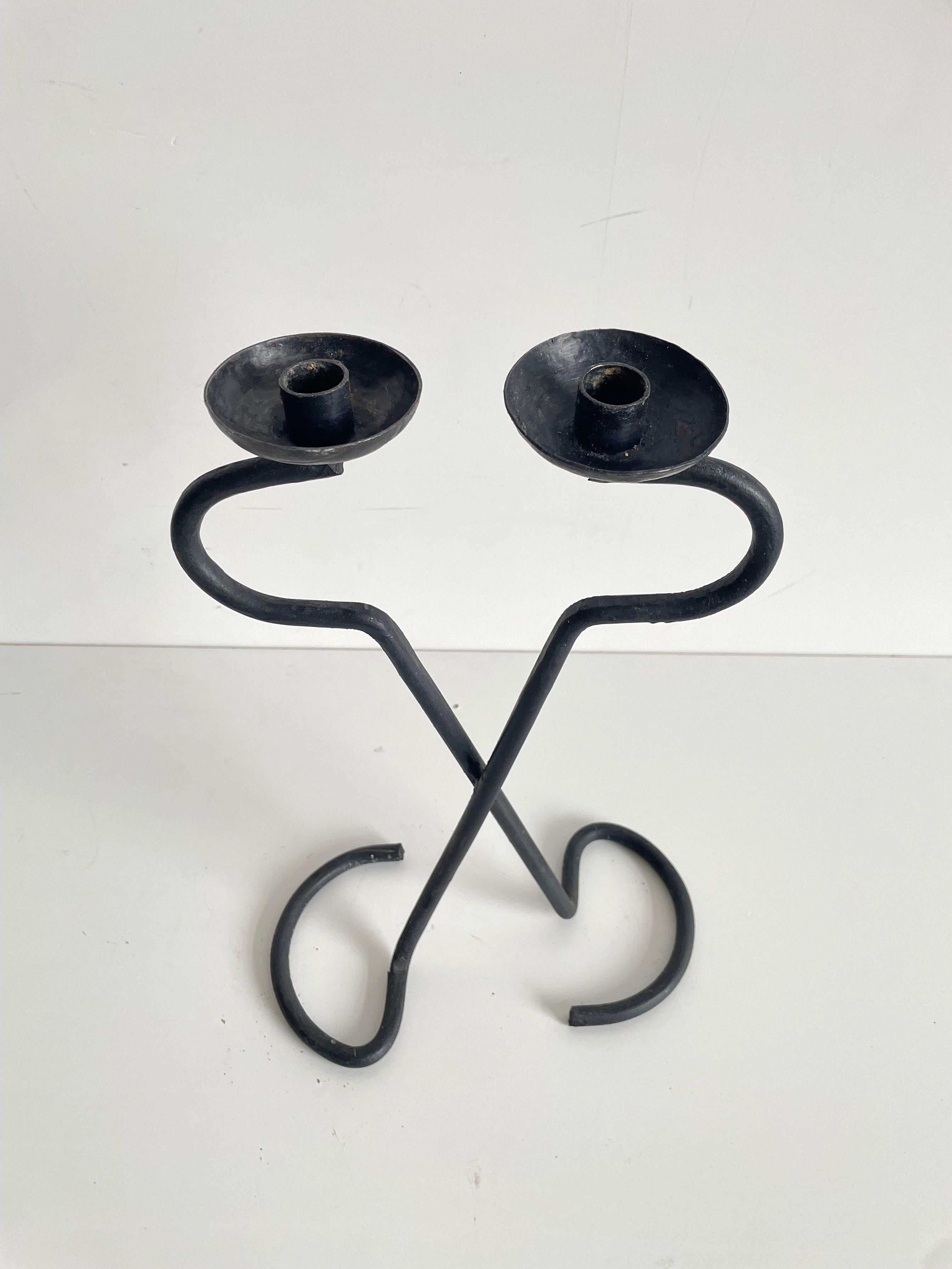 Sculptural brutalist wrought iron candle holder with two arms, each holding a circular plate measuring 8 cm in diameter with the candlestick holder in the center. Inner diameter of the candlestick holder is 2 cm

The candle holder was handcrafted
