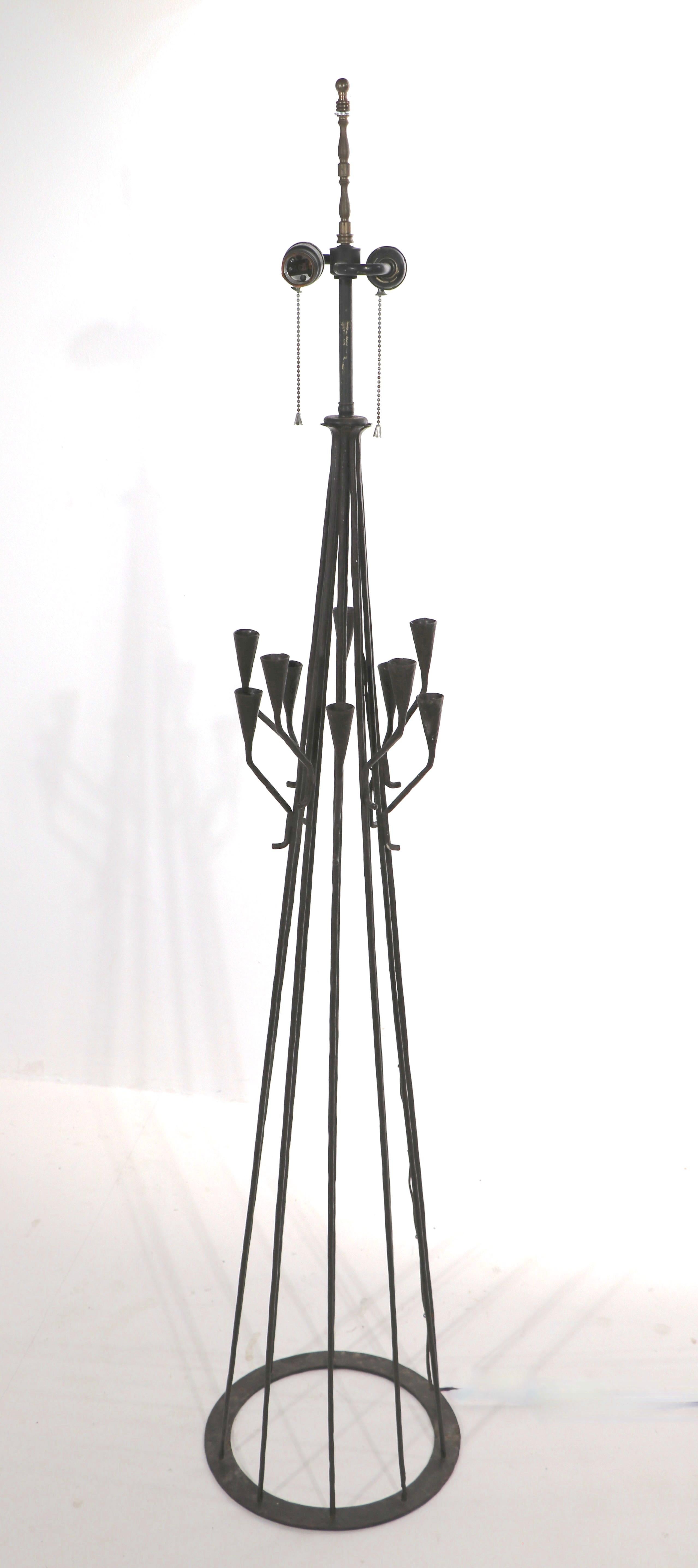 Interesting wrought iron floor lamp, having candle cup arms which extend off main center piece. The lamp has two standard size sockets ( working ). Marked Made in Portugal, impressed on circular metal base. Shade not included.