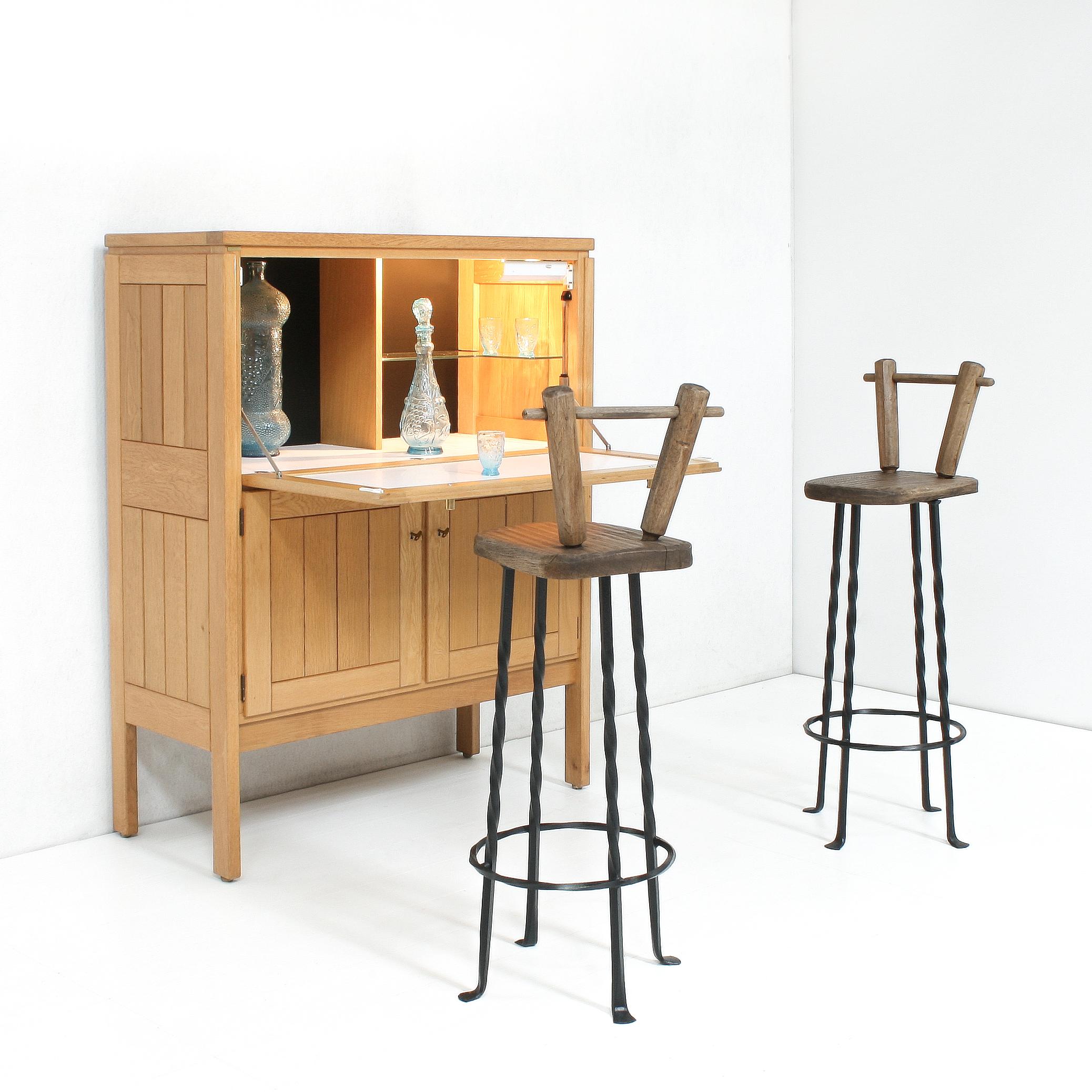 These crudely yet elegant made oak seat bar stools on a black forged iron base were made by hand in the 1970s.

The seat height is 75,5 cm.