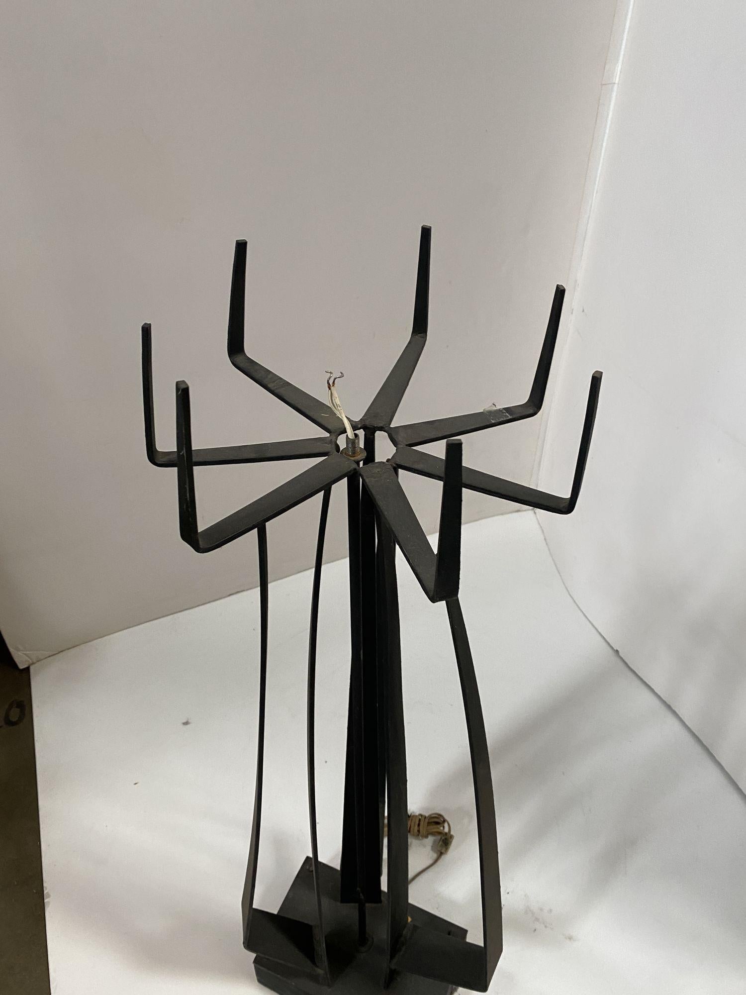 Lampe sur pied sculpturale en fer forgé de style brutal, fabriquée à la main, avec une base futuriste en forme de broche et 7 bras soutenant un abat-jour en verre. Le tout fixé sur une base cubiste noire de type mixed-media. Un excellent exemple de