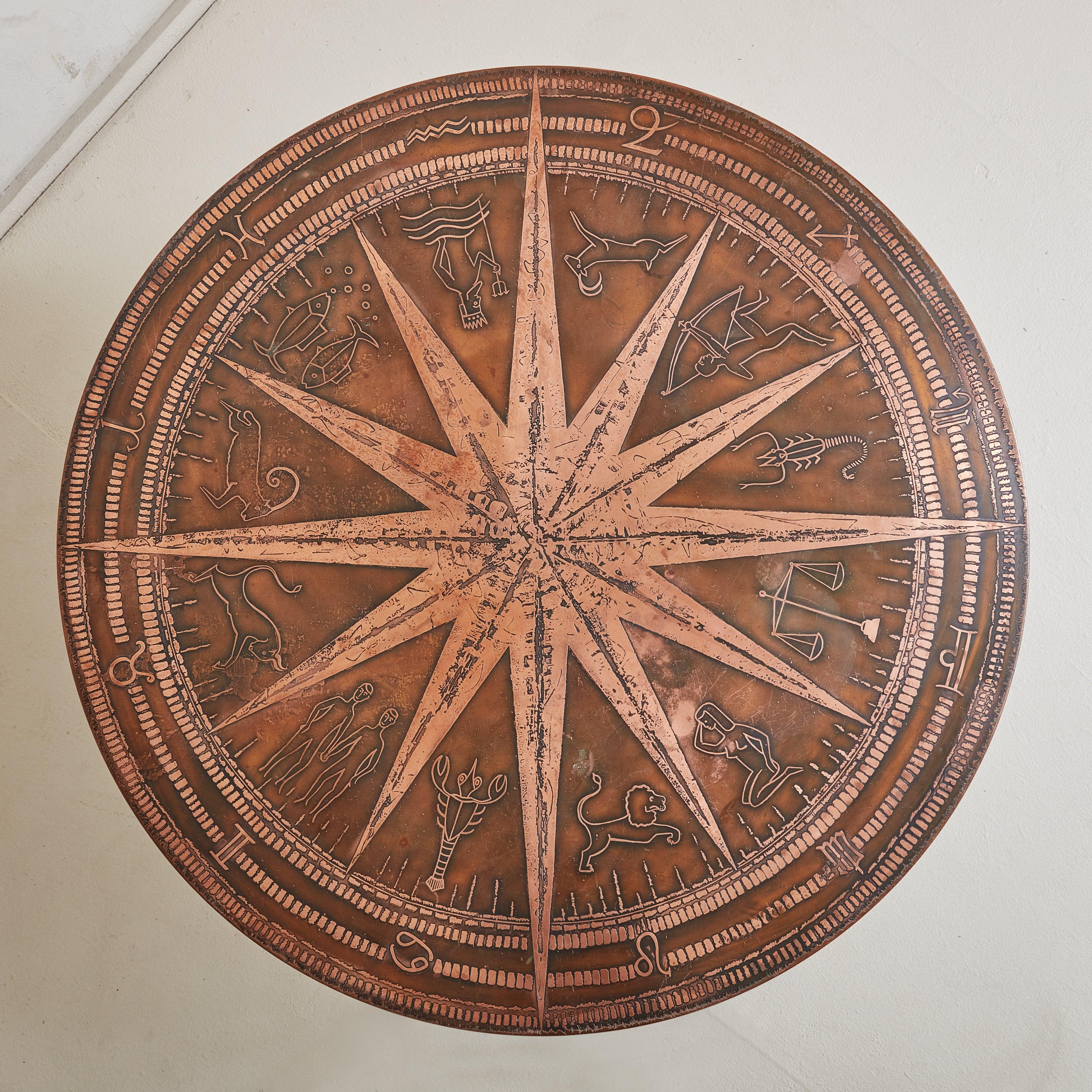 Une étonnante table basse brutaliste des années 1960 en provenance d'Allemagne. Le plateau rond en cuivre patiné bicolore est orné d'une grande étoile centrale, de motifs du Zodiac et de détails géométriques complexes. Un socle à quatre points en