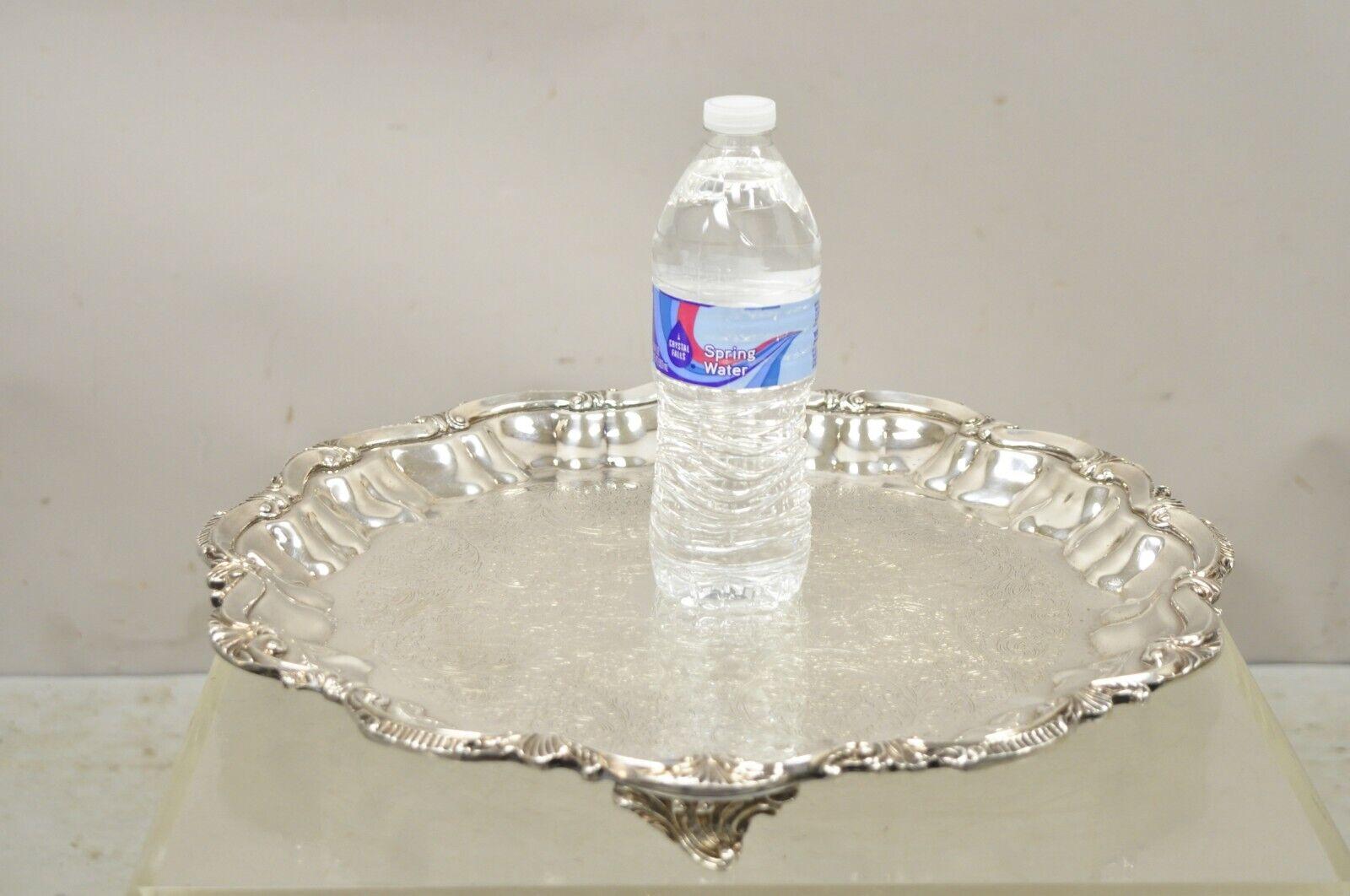 BSC English Silver Plated Victorian Style Round Scalloped Serving Platter Tray. Item features ornate Etched Center, Raised on 3 feet, Original Hallmark. Circa Mid 20th Century. Measurements: 1.5