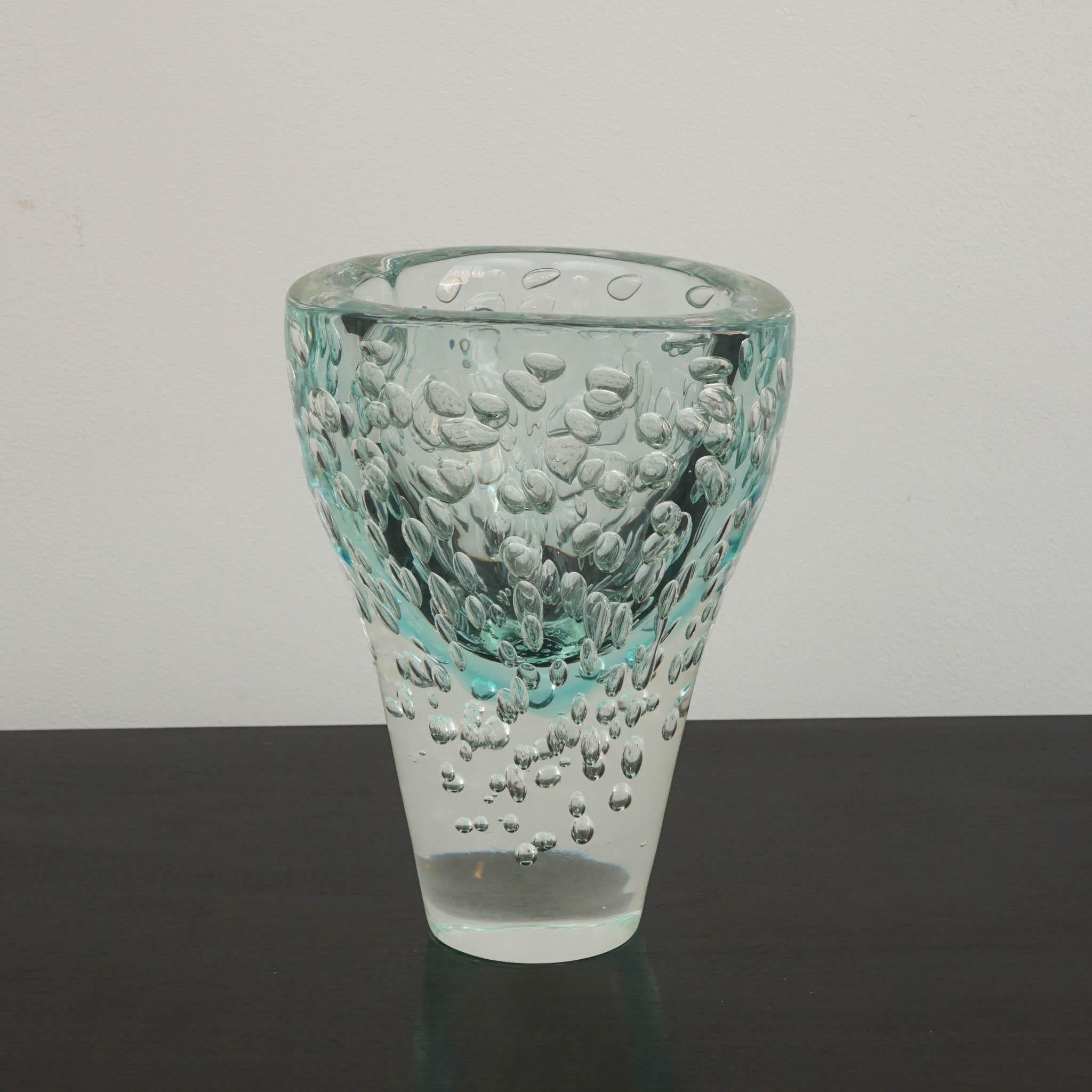 Este exquisito jarrón de cristal de Murano es una auténtica obra de arte, elaborada con maestría para evocar el grácil fluir y movimiento del agua. Su forma orgánica y ondulante se complementa con una base de cristal transparente, que confiere a la