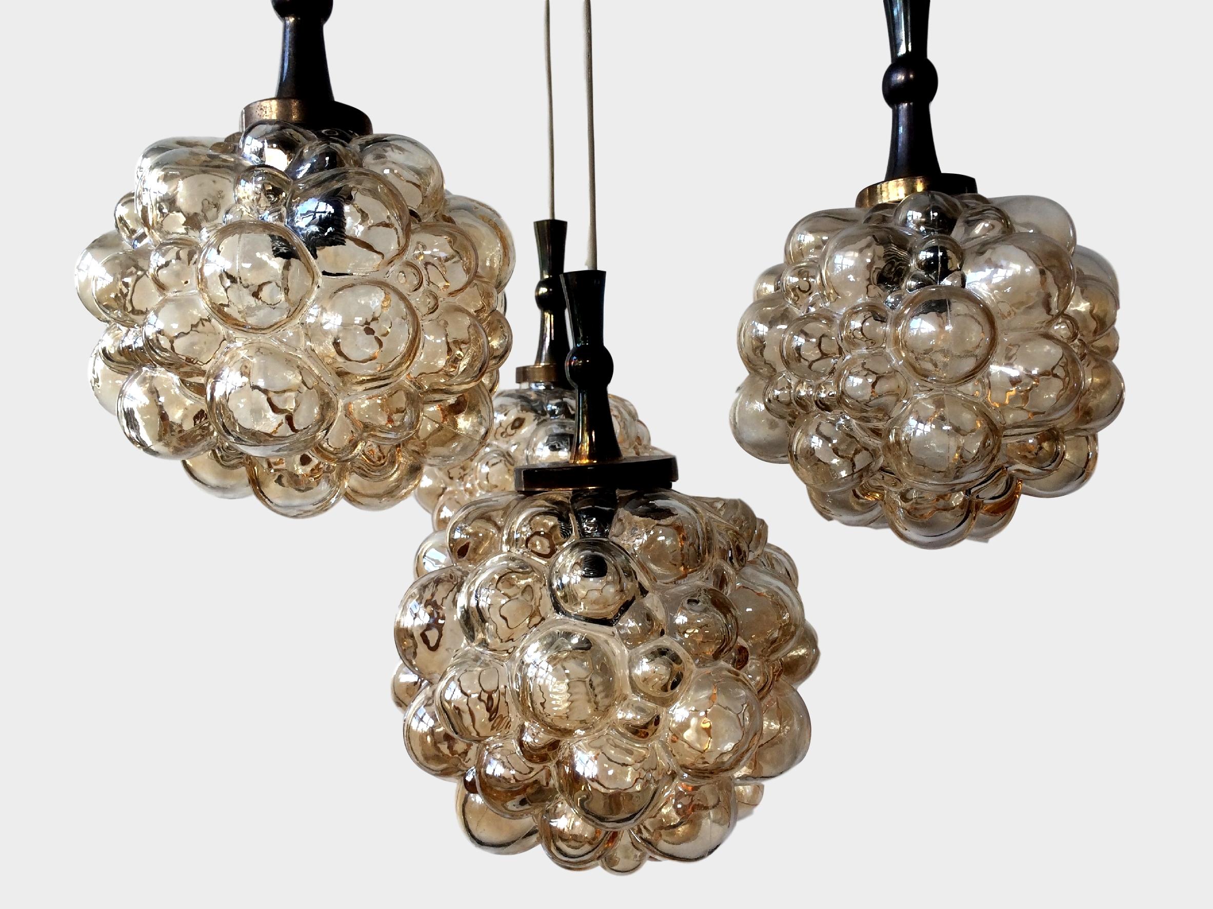 Impressive brass and amber toned glass bubble globe, four pendants chandelier.

Thick amber colored bubbled glass globes, designed by Helena Tynell, by Limburg, Germany, circa 1960s.

Larger central pendant measures 20cm tall, 22cm wide, three
