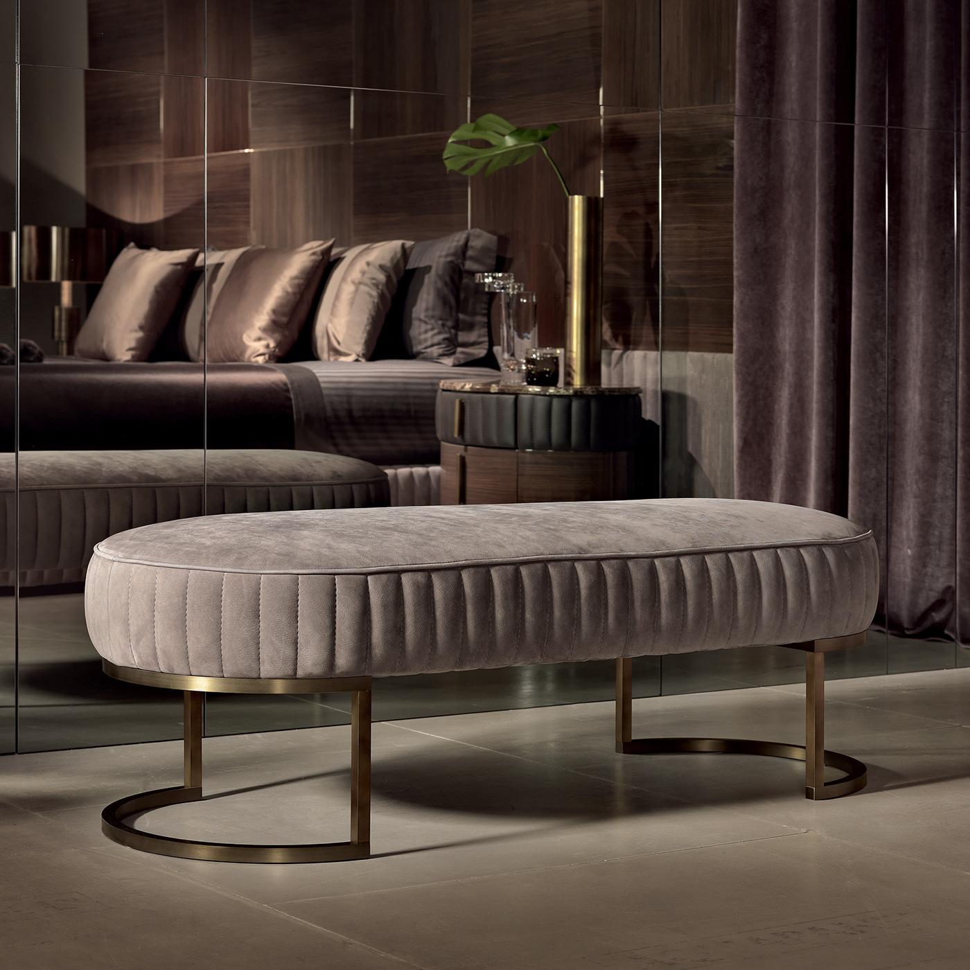 Merging midcentury austerity with Hollywood glamour, the upholstered gray leather seat of this elongated bench (in the picture fabric nabouk leather in tortora 215 color) is balanced on delicately semicircular burnished brass legs. A welcoming seat