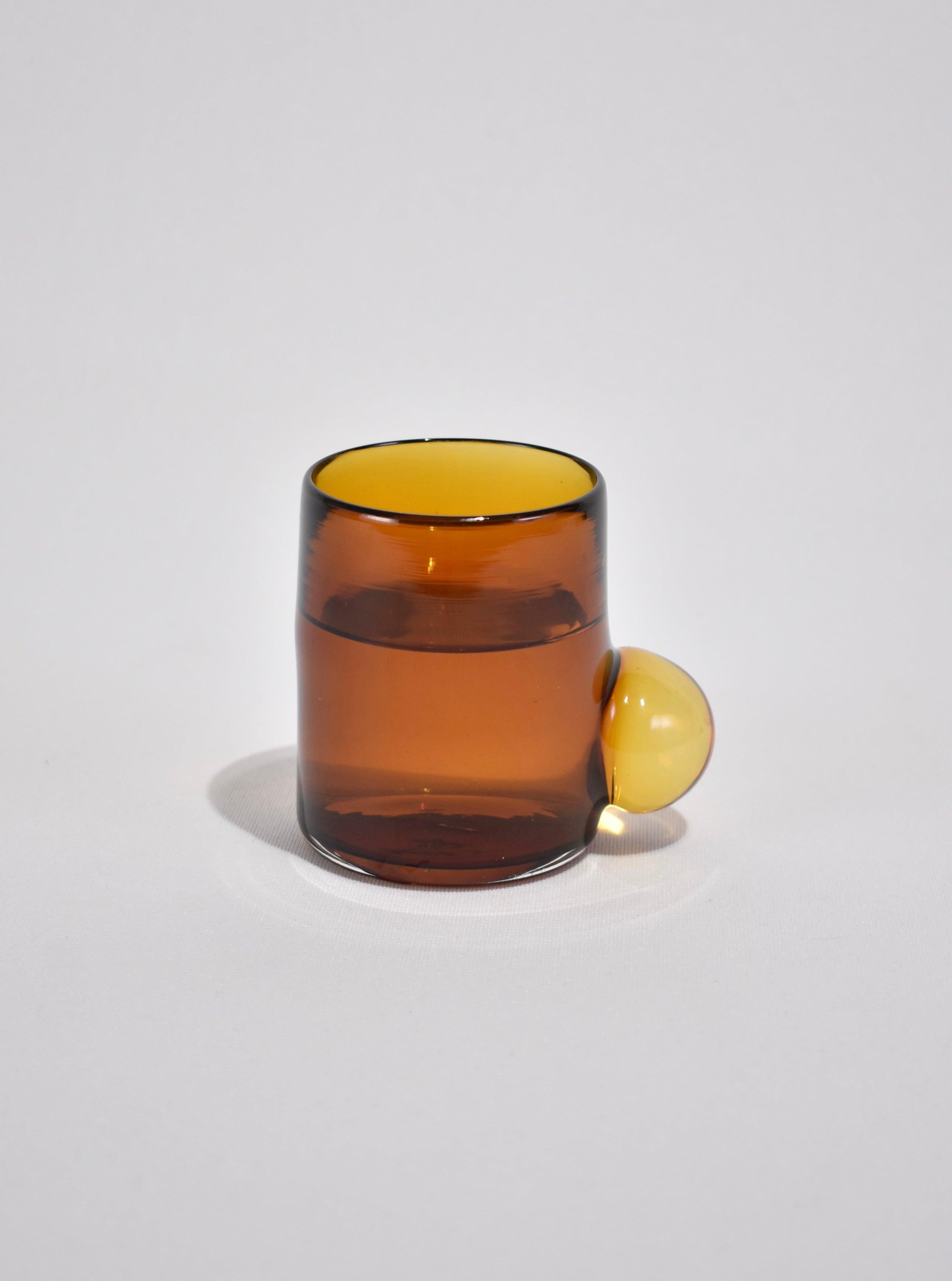 Blown glass tumbler in amber with a clear bubble handle. Perfect size for water, wine, juice, or spirits. Handmade in USA by Grace Whiteside of Sticky Glass.

Please note: Due to the handmade nature of this cup, subtle variations in form and
