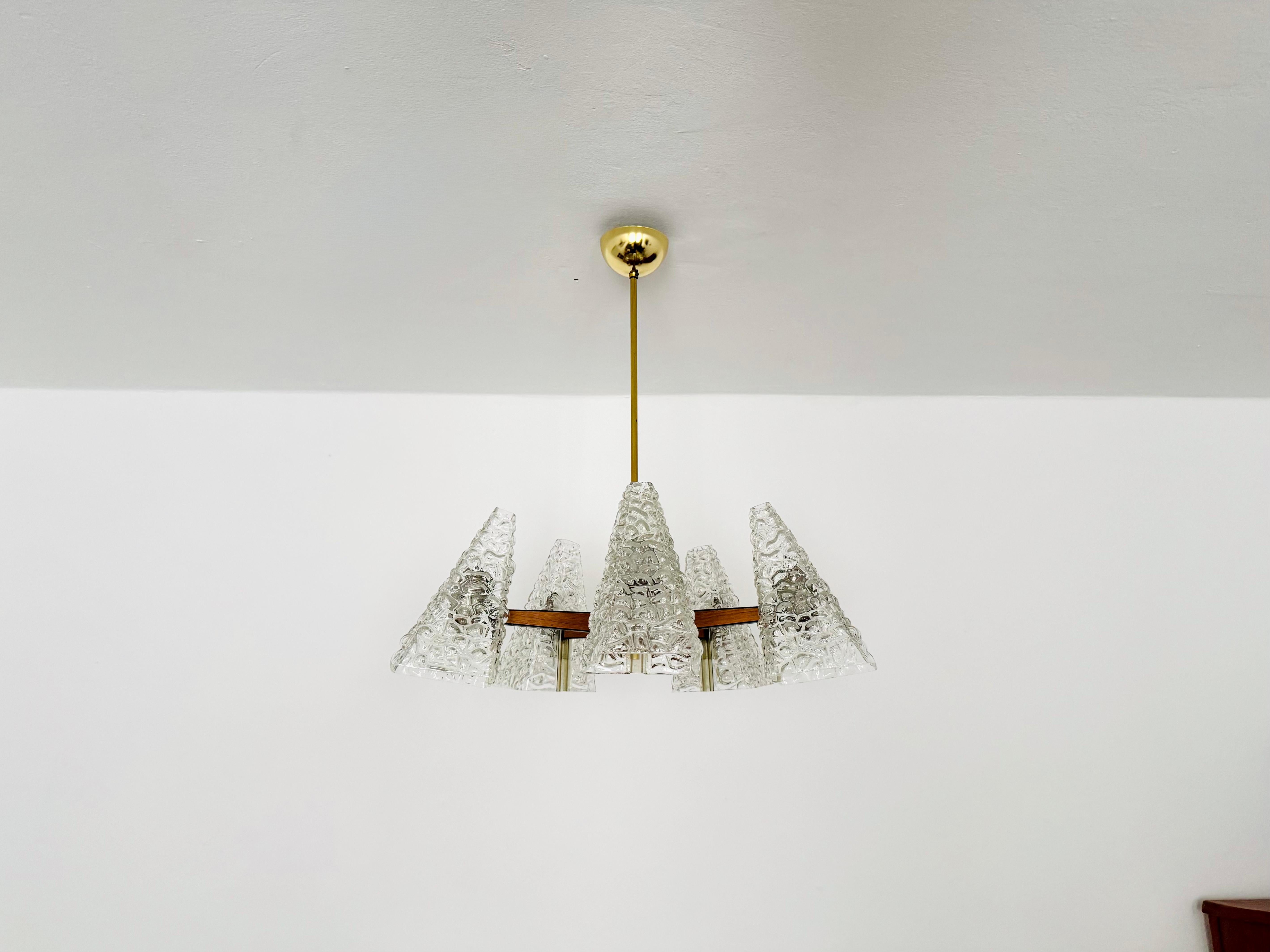 Lustre d'une beauté exceptionnelle datant des années 1950.
La lampe est très rare et impressionne par l'amour des détails, comme le bois de teck dans des supports en métal noir.
Une lampe étonnante et un véritable atout pour toute maison.
Le verre