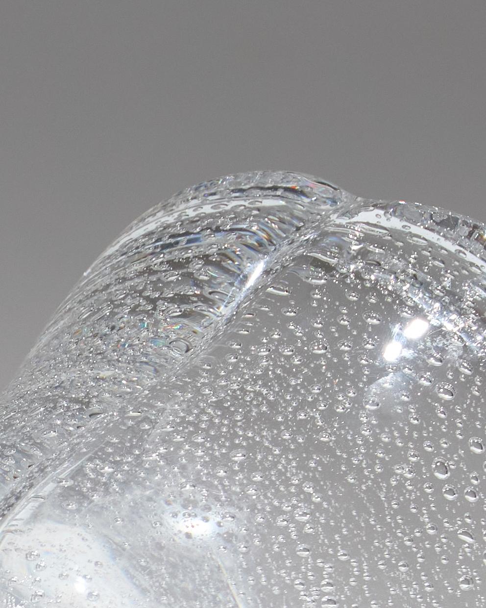 Vase en verre épais soufflé, orné d’inclusions de bulles régulières dans la masse, caractéristique du savoir-faire de Daum. En forme légère de mouchoir, signé Daum Nancy France avec croix de Lorraine. En très bon état. Pièce authentique de la