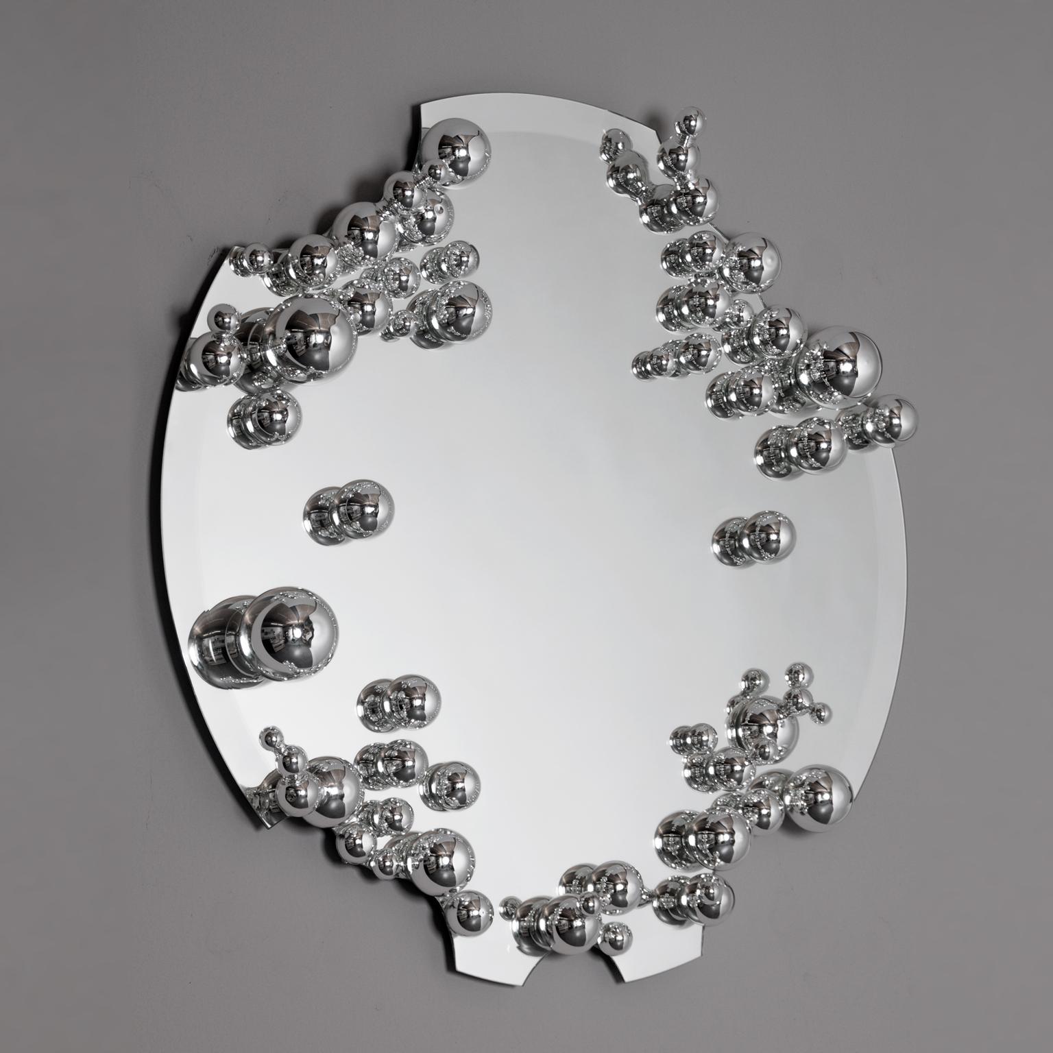 The mirror, carefully cut by hand, explores the dichotomy between object and reflection. The work is adorned with delicate bubbles of silvered glass with the traditional Venetian techniques that play between reality and reflection thanks also to a
