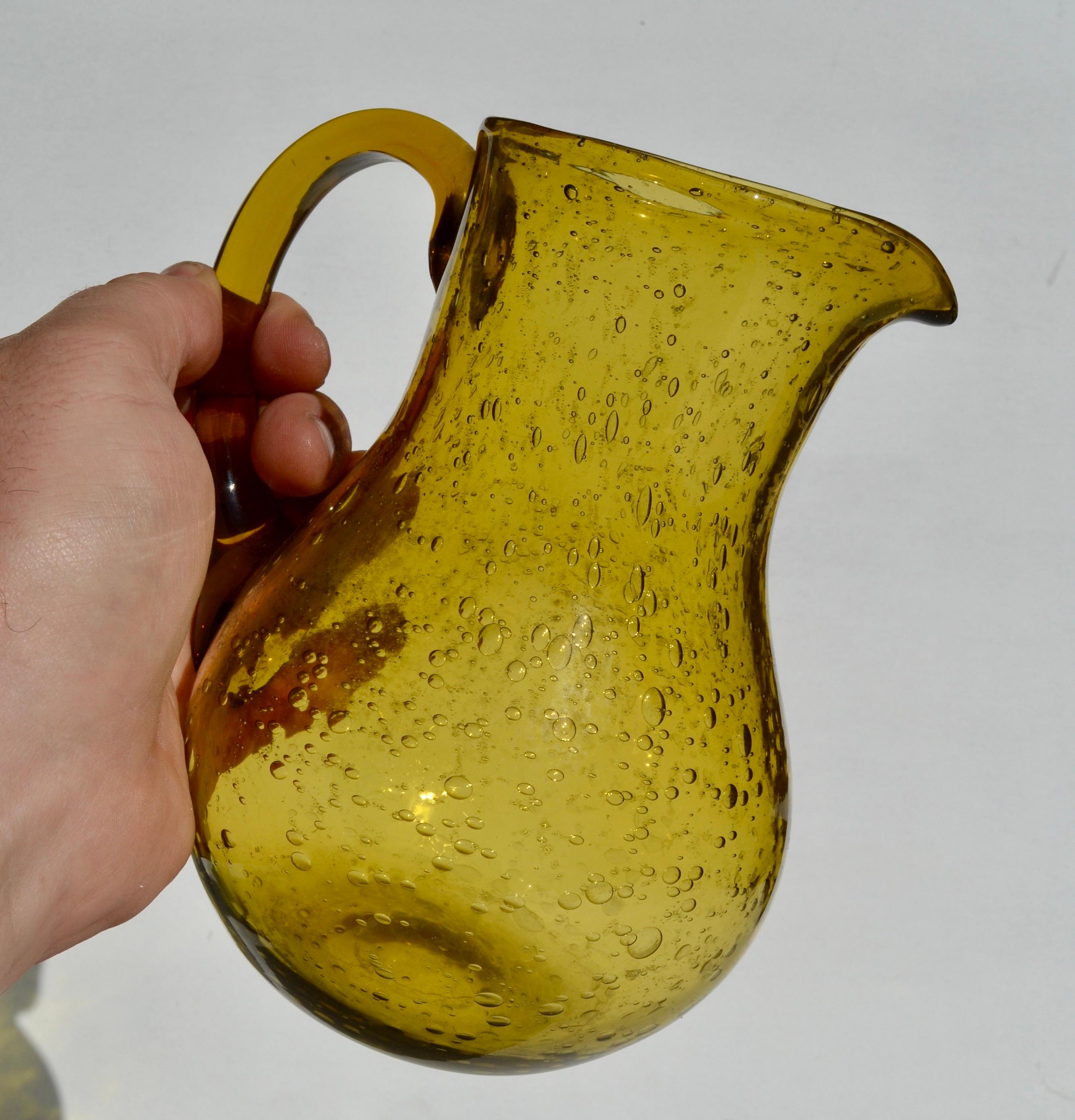 An elegant hand-blown glass pitcher by Biot, France, dating from the 1970s. This piece showcases Biot’s signature bubbled glass effect, created by tiny air inclusions that give the surface a distinctive texture and brilliance. Crafted in a warm