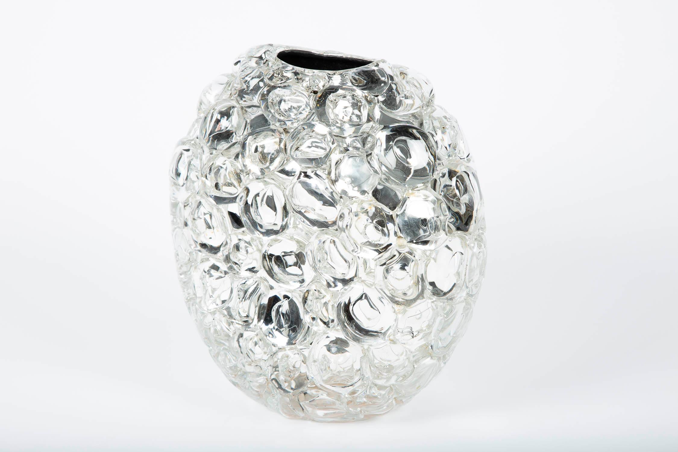 Bubblewrap in Clear is a hand-blown and sculpted vase created from clear glass, with a mirrored interior by the British artist Allister Malcolm. Playful yet elegant, Malcolm has formed oversized bubbles on the exterior of this handcrafted and blown