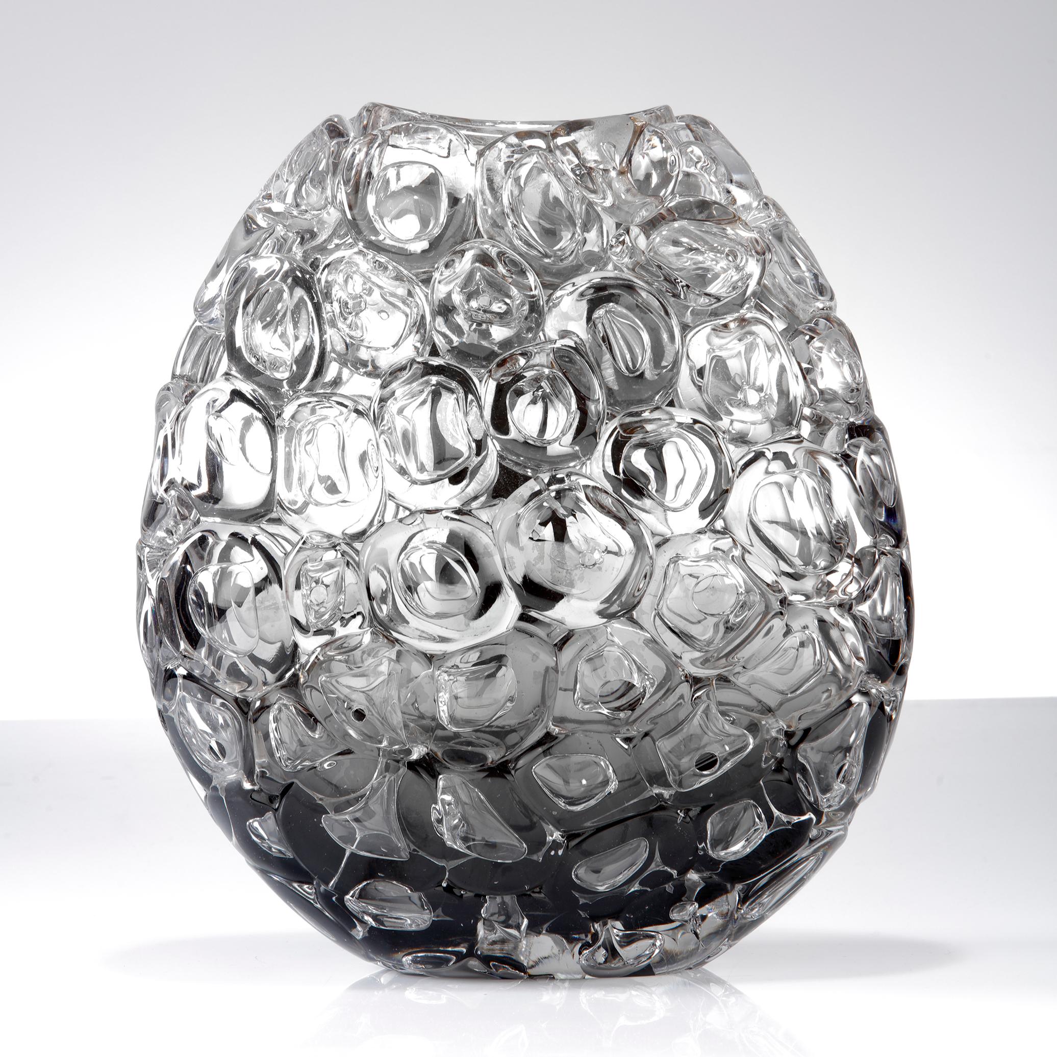 Bubblewrap in Monochrome I is a hand blown and sculpted vase created from clear and grey glass, with a mirrored interior by the British artist Allister Malcolm. Playful yet elegant, Malcolm has formed oversized bubbles on the exterior of this