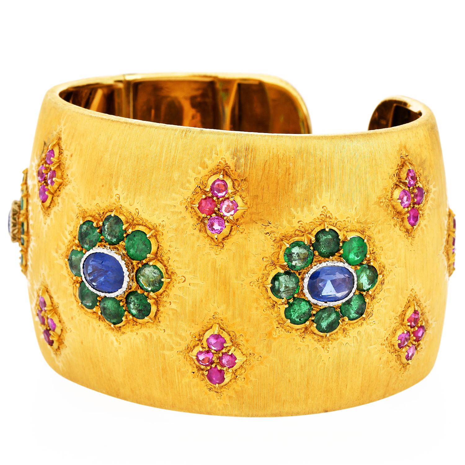 Presenting a rare wide cuff bracelet from Buccellati. It is forged in 18K yellow gold with satin finish work popular design of the Mario Collection from the house of Buccellati.

The bracelet is decorated with precious stones Rubies, Emeralds, and