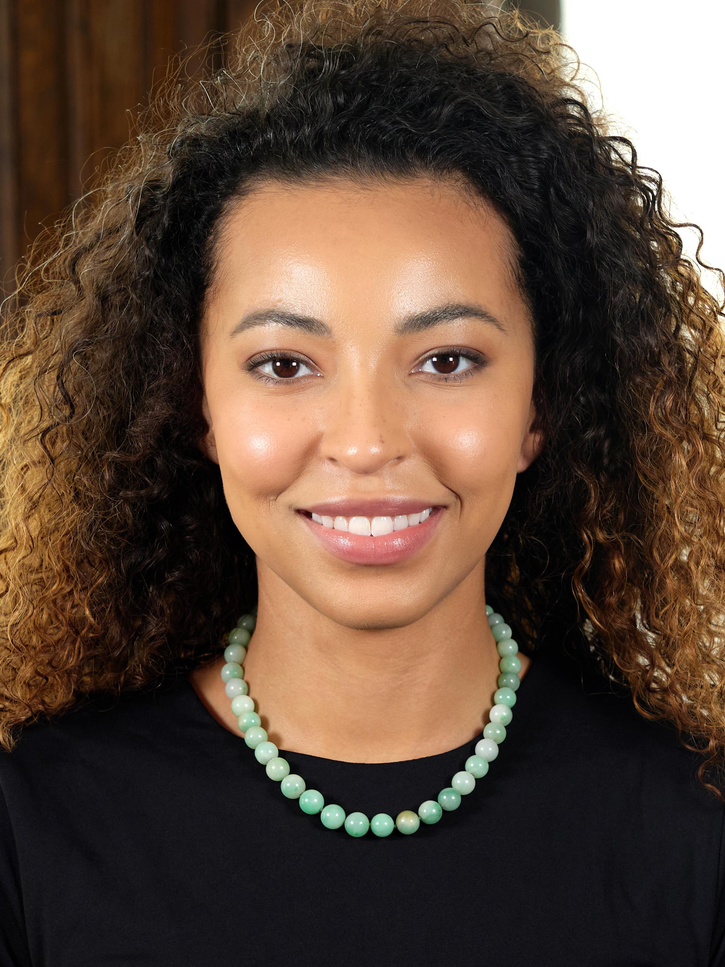 Bestehend aus abgestuften Jadeperlen, die auf eine geknotete grüne Seidenkordel gefädelt sind.
Transluzentes Hell- bis Mittelgrün mit dezenter Sprenkelung
Mit einer Größe von 7,0 bis 10,5 mm rund
Abgerundet durch eine stilisierte ovale Goldspange
In