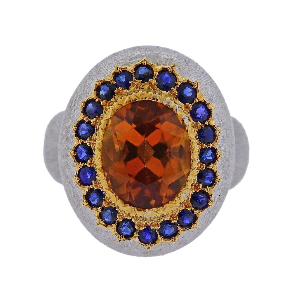 18k white gold cocktail ring , crafted by Buccellati, set with a 10.5mm x 8.8mm citrine centerpiece, surrounded with blue sapphires. Ring size - 6.5, ring top is 21mm x 17mm. Weight is 12.1 grams. Marked 750, Buccellati, Italy, 18k, A5211.