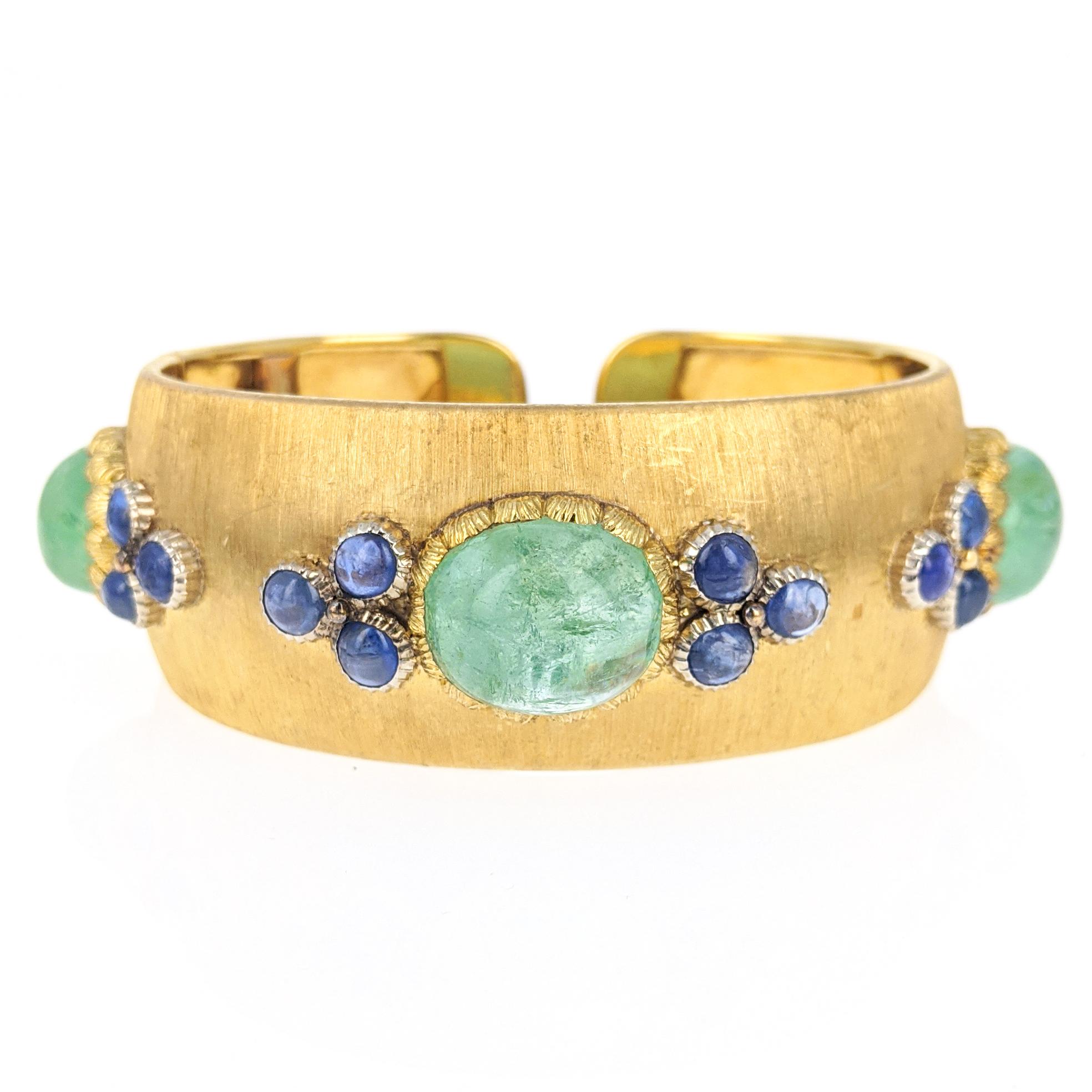 This Buccellati cuff bracelet features three cabochon emeralds, each flanked by trios of round cabochon sapphires. Mounted in 18 karat yellow gold with brushed finish. Signed Buccellati, with scratchmark and marked 750. Inner circumference measures