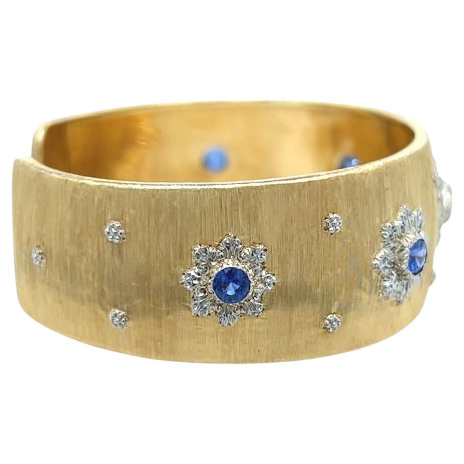 An 18 karat yellow and white gold and sapphire bracelet, Buccellati.  The “Macri” bracelet designed as a brushed yellow gold open backed cuff applied with five (5) graduating rosettes of white gold, each set with a round faceted sapphire, further