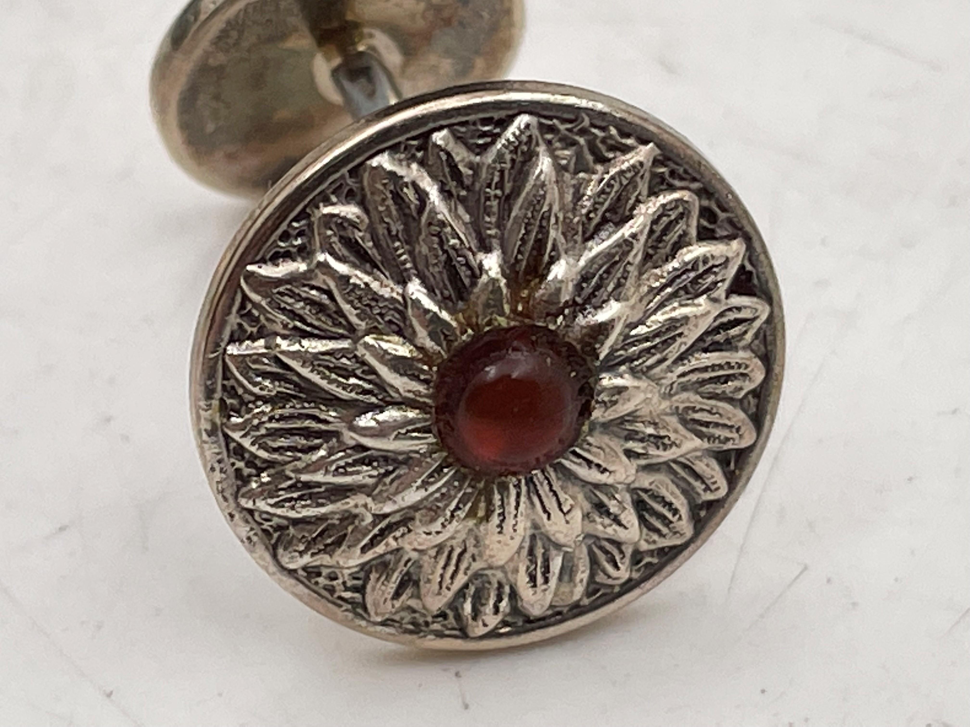 Gianmaria Buccellati, Italian, pair of sterling silver cufflinks, shaped as a sunflower, with a red stone at the center, in a beautiful floral motif, measuring 2/3'' in diameter, and bearing hallmarks. Sold in its original box, never used.

Mario