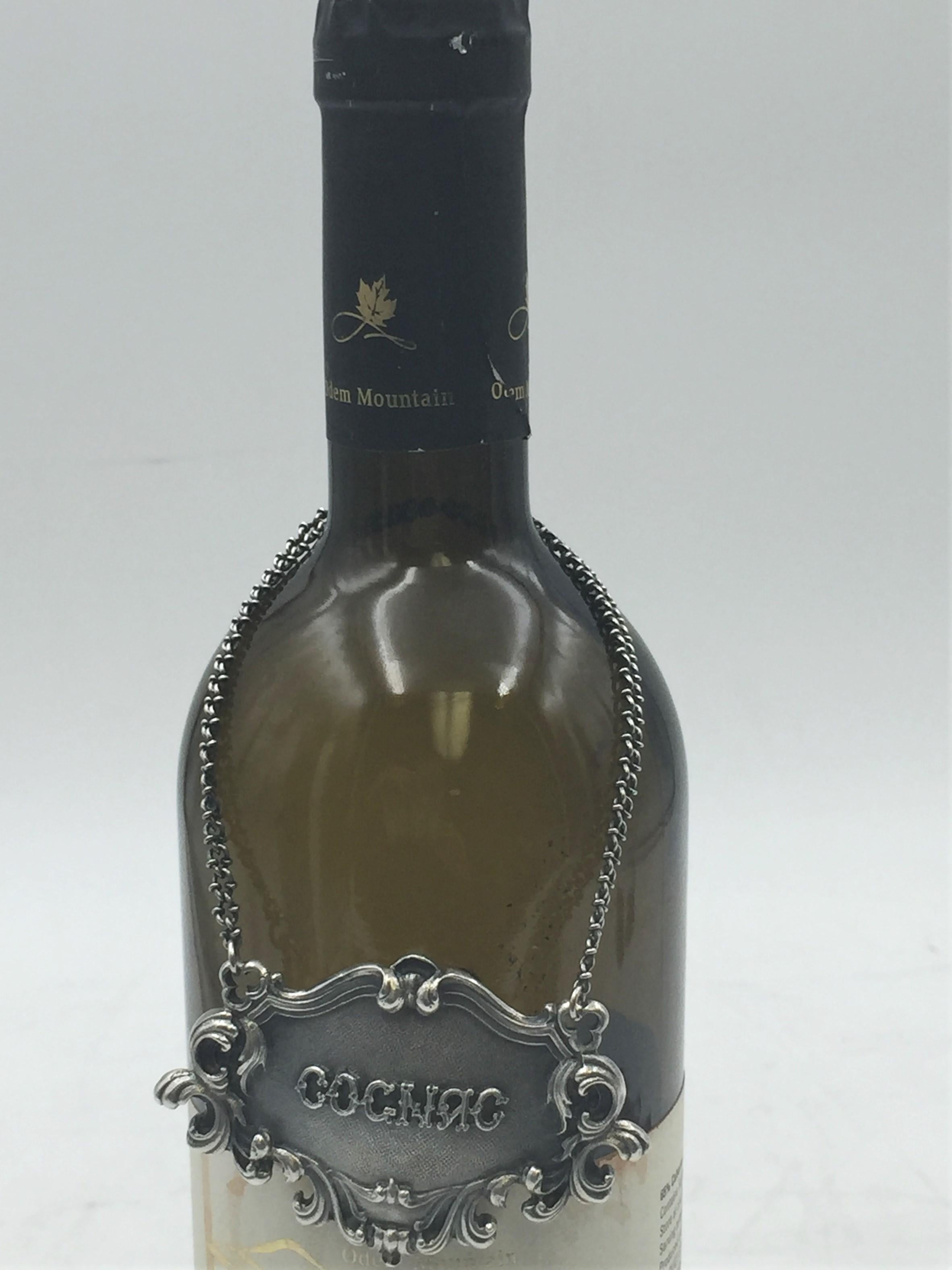 Rare Buccellati sterling silver claret bar jug label. COGNAC embossed on the front in the center.

Marks on the back: Gianmaria Buccellati (signature and Italian maker's mark), ITALY, 925 (encircled silver purity mark).

It measures 3in x 2in.