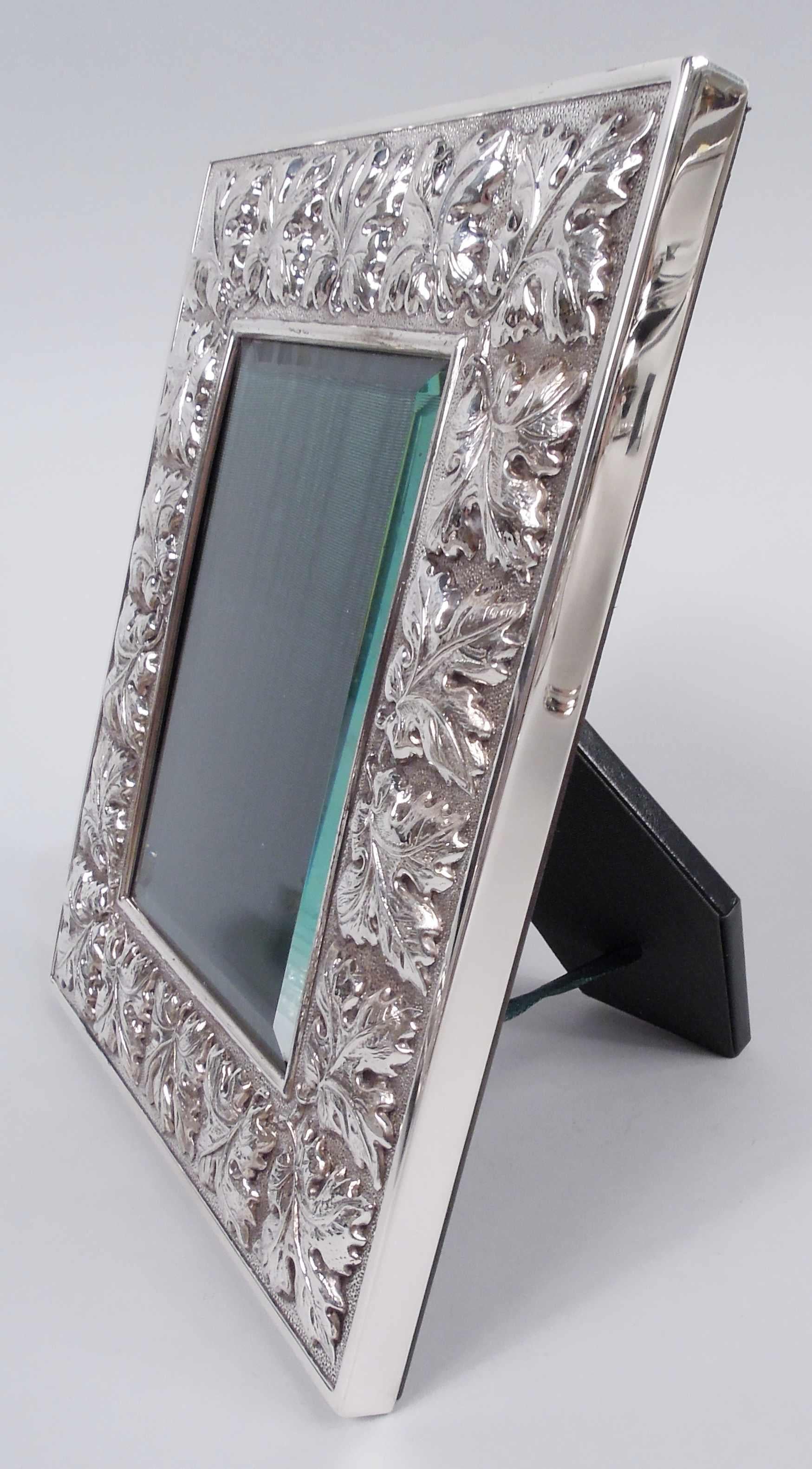 Modern Classical sterling silver picture frame. Made by Buccellati in Italy. Rectangular window in wide and cast surround with big and bold leaves in orderly wraparound arrangement on stippled ground. Sides plain. With beveled glass, silk lining,