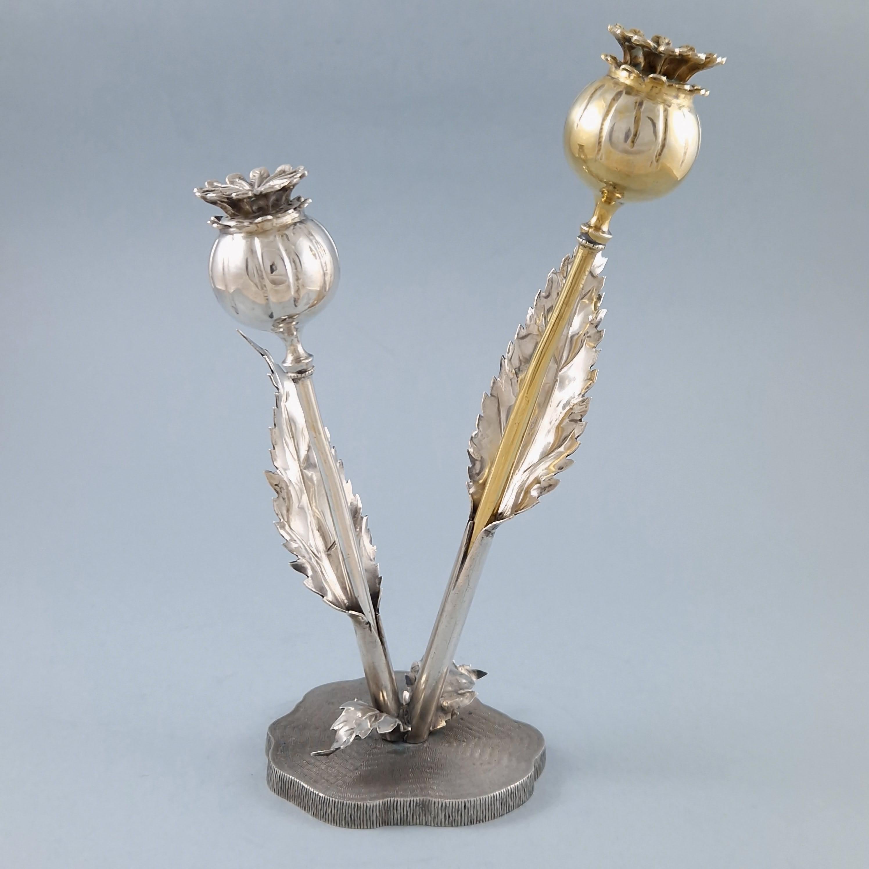 This late 20th century salt and pepper shaker set, designed to look like a poppy plant sprouting from the base, was produced by Buccellat

The poppy pods hold the salt and pepper and detach for use

800 silver hallmark
Measures: Height: