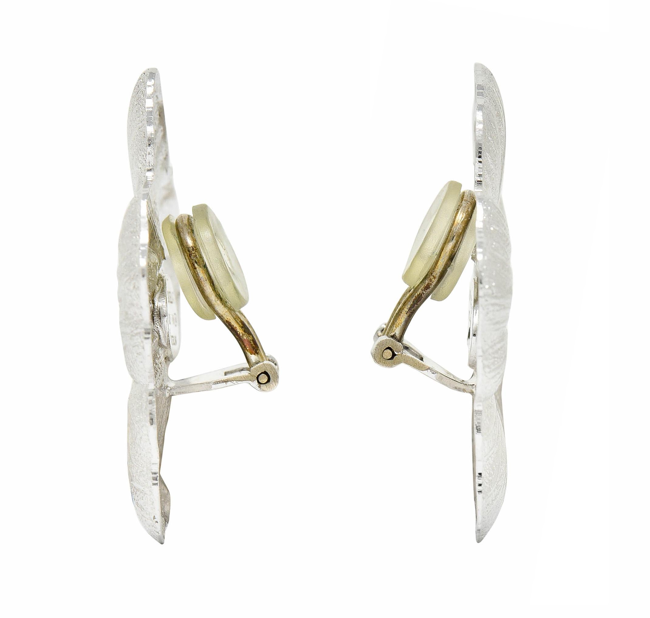 Ear-clips are designed as repoussè rendered gardenia blossoms

With intricate petal veining and a clustered vermeil appliquè center

Completed by hinged omega backs

With Italian assay marks and stamped for sterling silver

Signed Buccellati

From