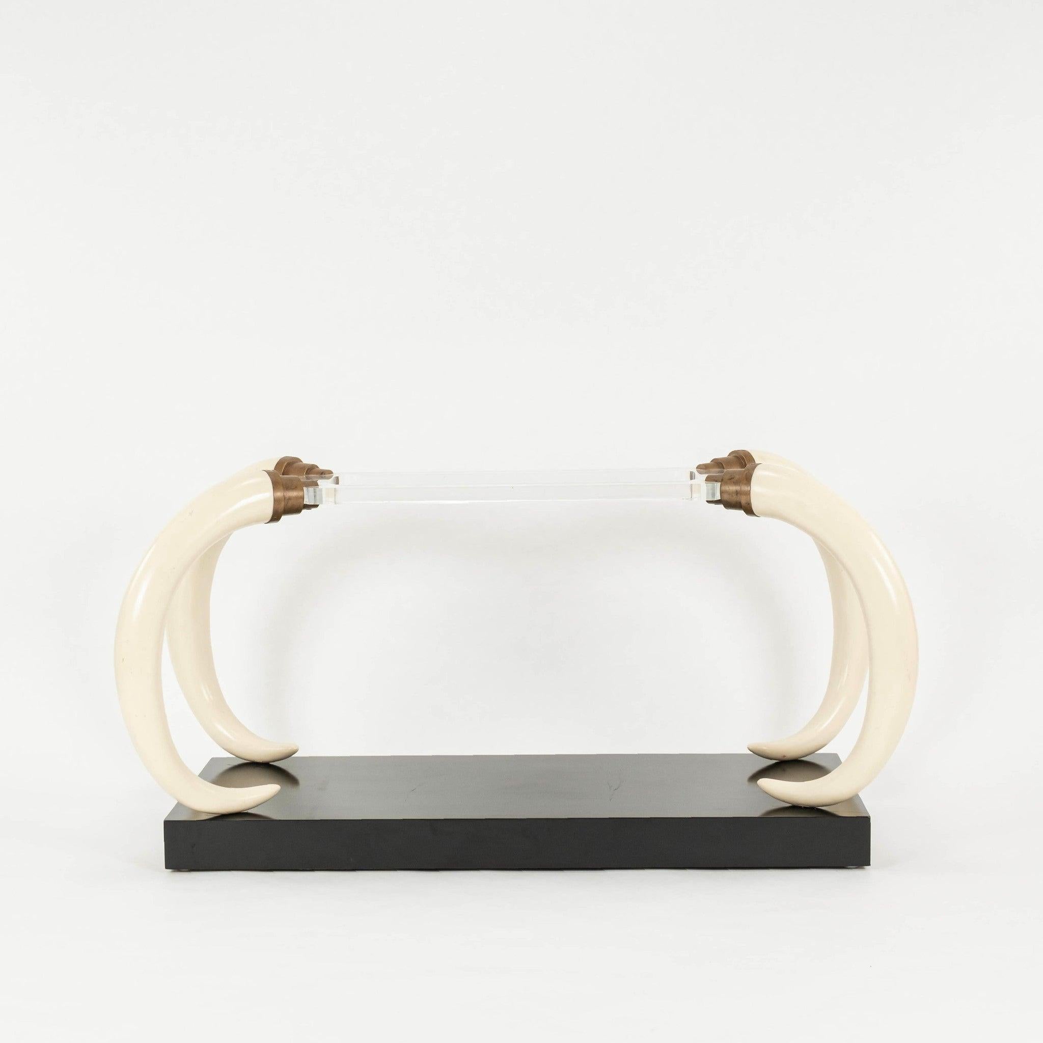 Late 20th Century signed  Bucci lucite and faux tusk console table. This console table features a black-painted wooden base, faux-painted elephant tusk legs, brass hardware, all supporting a thick slab of lucite.