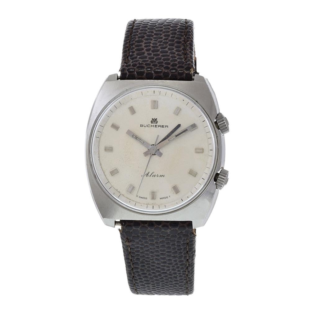 Voici la montre alarme Bucherer 1970 Large en acier inoxydable, une pièce d'horlogerie saisissante qui respire le charme vintage et la fonctionnalité. Logée dans un robuste boîtier en acier inoxydable en forme de tonneau, cette montre affiche une