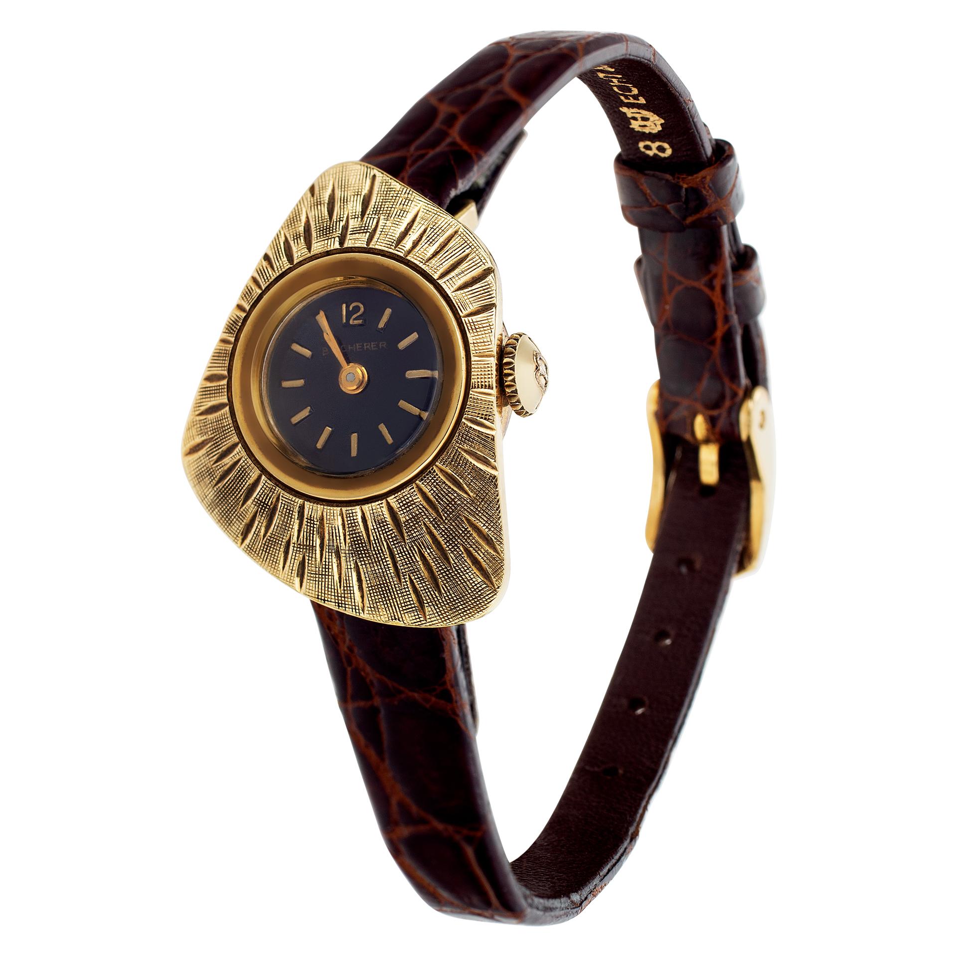 Vintage Bucherer in 18k and trapezoid shaped case with textured design bezel with a black dial set with applied stick hour markers on a leather strap on a gold fill tang buckle. Manual. Circa 1960s. Fine Pre-owned Bucherer Watch.