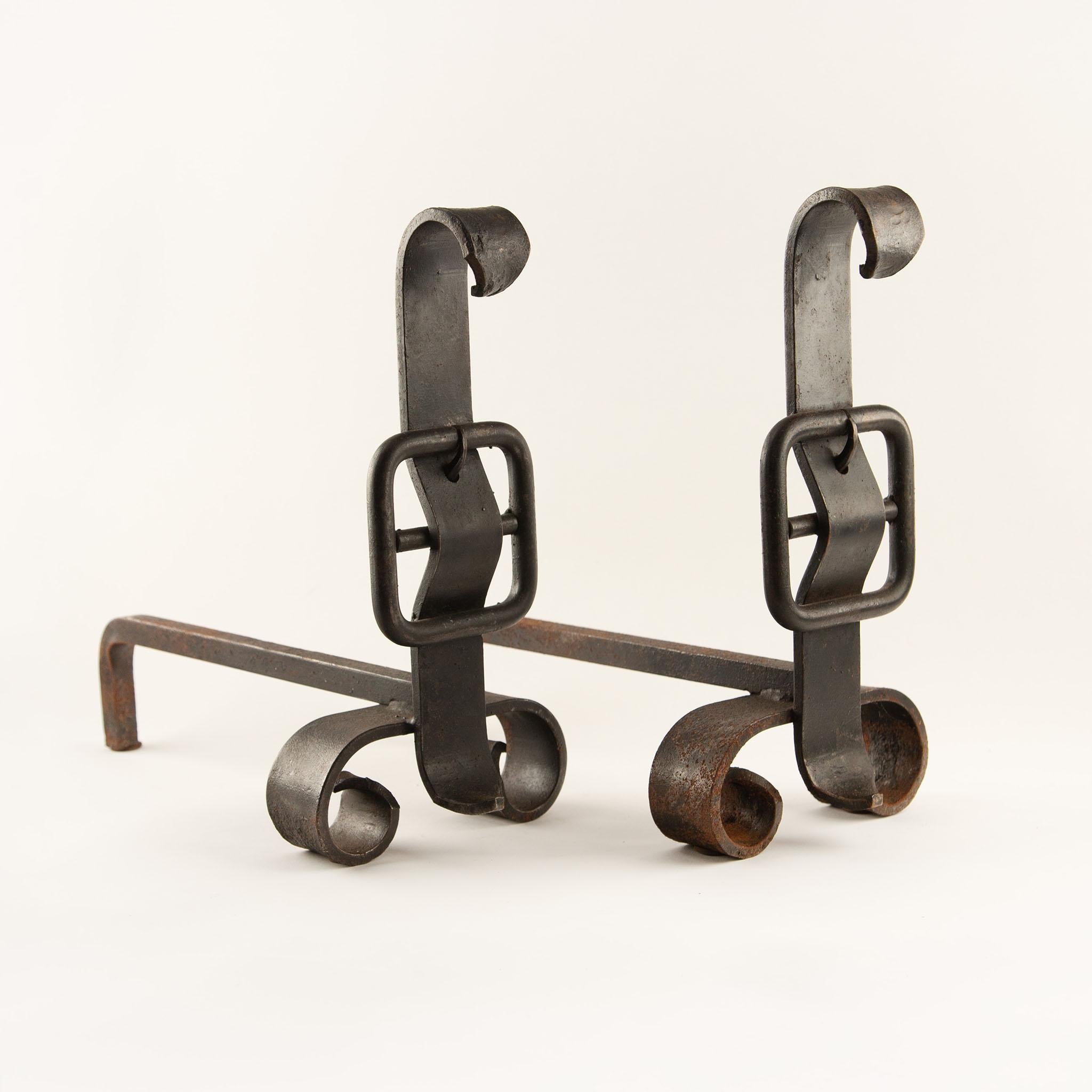 Paire de chenets à boucles en fer forgé, 19e siècle
Forgés en fer massif, ces chenets de cheminée se caractérisent par de robustes barres de billettes se terminant par des pieds à volutes serrés et des montants percés par des cadres carrés à