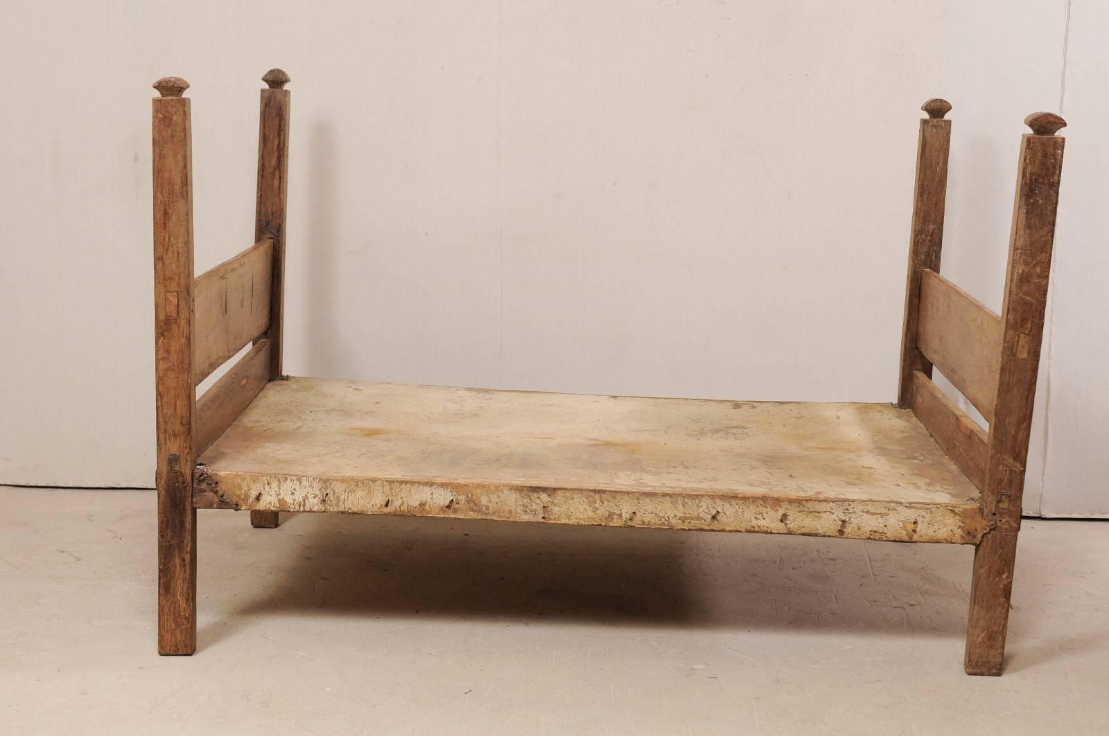 A vintage Brazilian cowhide and wood frame single size daybed. This Brazilian bed, which is sized between a twin and double, features simplistic wooden foot and headboards, four squared legs, which extend upward into posts with carved finials