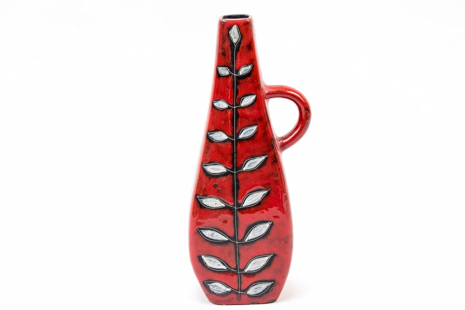 Bud vase in red earthenware with one handle, in flat bottle shape.
Decor of a stylized plant with white leaves.

“Italy” engraved on the bottom.

Italian work realized in the 1950s.