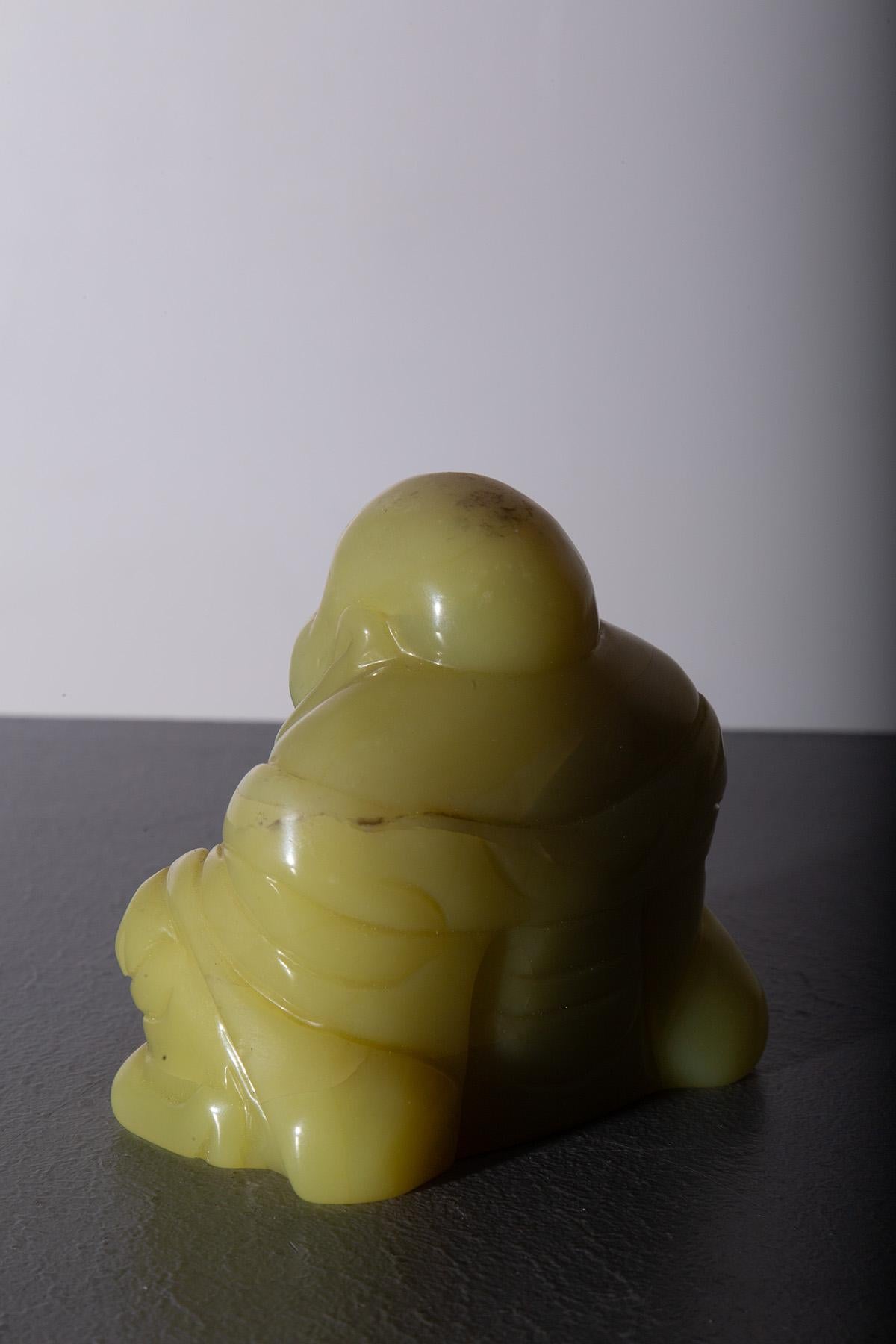 This fascinating Budai Buddha, carved from yellow jade, represents an iconic figure in Eastern art and spirituality. The jade, with its warm and luminous yellow hue, symbolizes prosperity, happiness, and health. The Buddha himself, also known as the