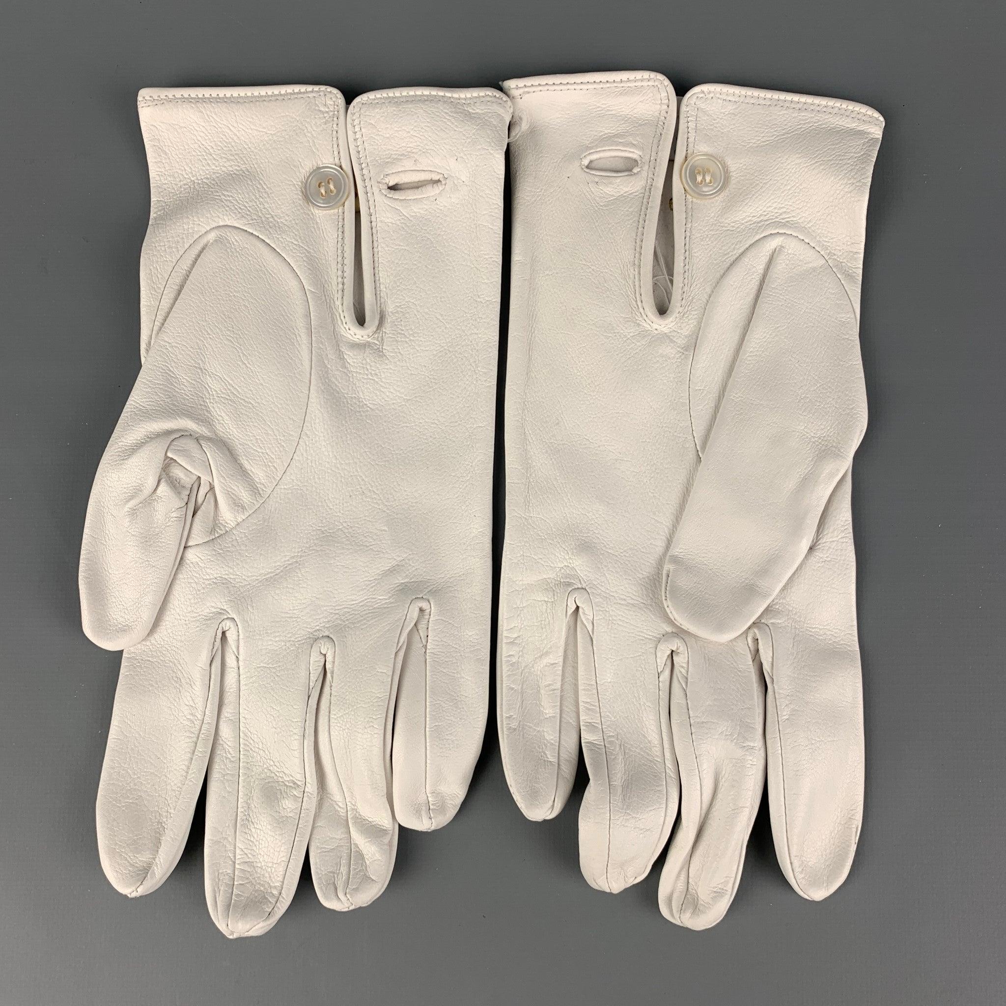 BUDD gloves comes in a white leather featuring a buttoned closure. Made in England.
Good Pre-Owned Condition. Discoloration at front. As-Is.  

 Marked:  9 

 Measurements: 
  Width: 4 inches Length: 9.5 inches 
   
 Sui Generis Reference: 118039
