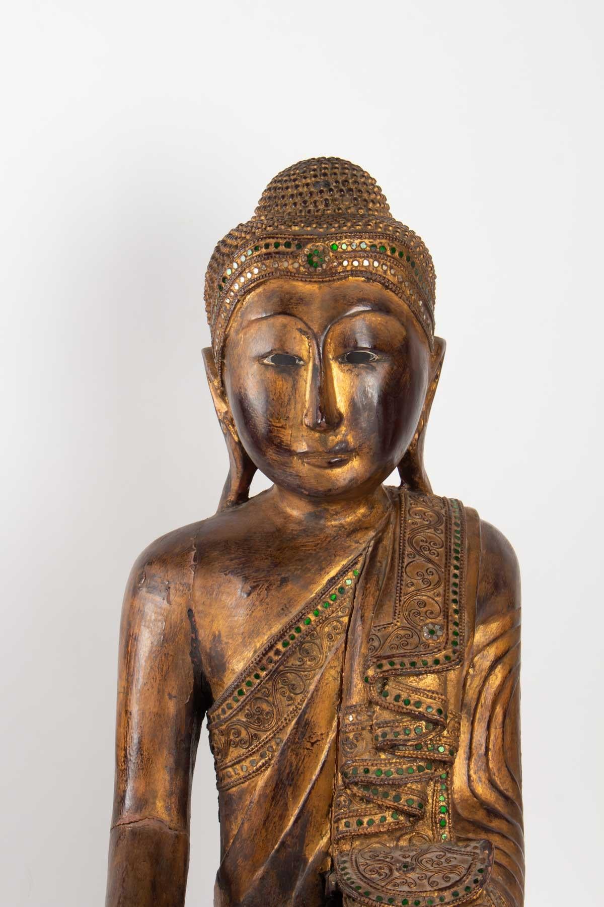 Wooden Buddha carved Thailand, mid-20th century, slot in the wood above the hand and under the elbow. Green and white mirror inlay.
Measures: H 70cm, W 57cm, W 37cm.