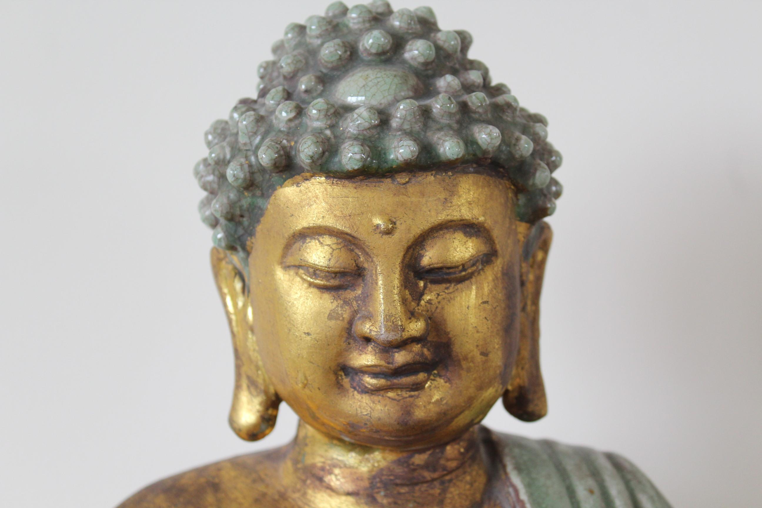 A tranquil light green glaze with gold leaf adorn this sitting Buddha statue in meditation position. Bringing happiness and good fortune this Buddha is seated with legs crossed with his right hand lowered, long fingers joining downward in the earth