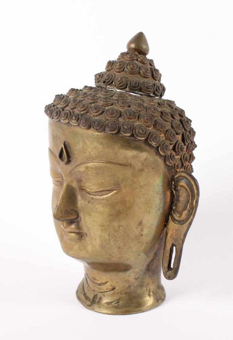 Buddha's Head is a beautiful bronze, realized in India in 20th century.

This is an amazing representation of a smiling Buddha, with curly hear and the typical cranial knob called Ushnisha, comes off.

In very good conditions except a minor loss