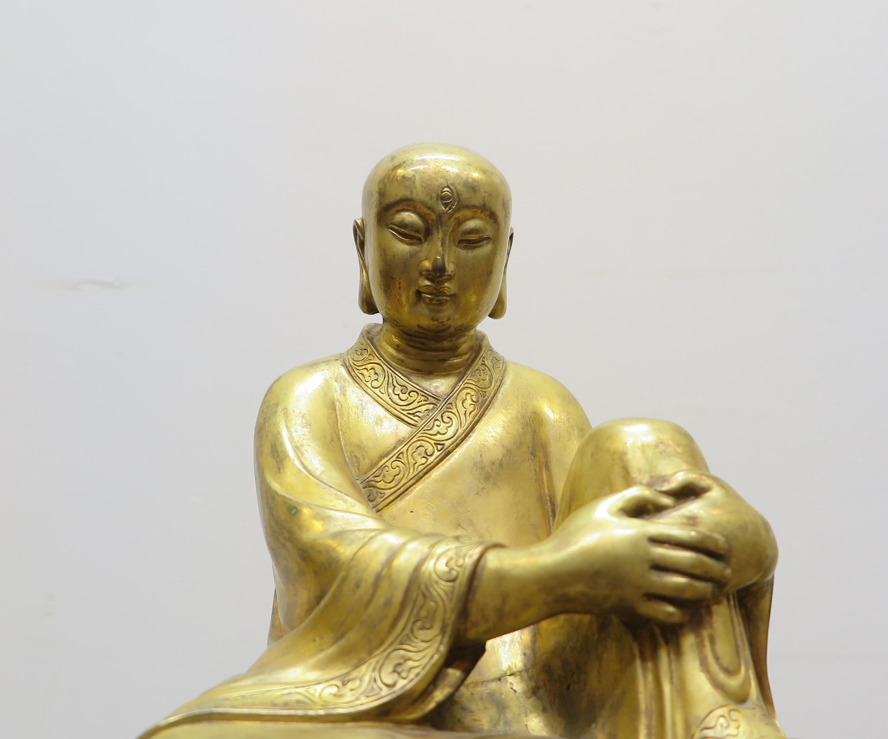 Gilded Bronze Buddhist Buddha statue. Serene casting of Enlightened Buddha Buddhist Monk seated on altar bench. A very sensitive detailed capture in bronze gilded with 24 karat gold leaf. Exquisite countenance. Detail etching surrounds the edge of